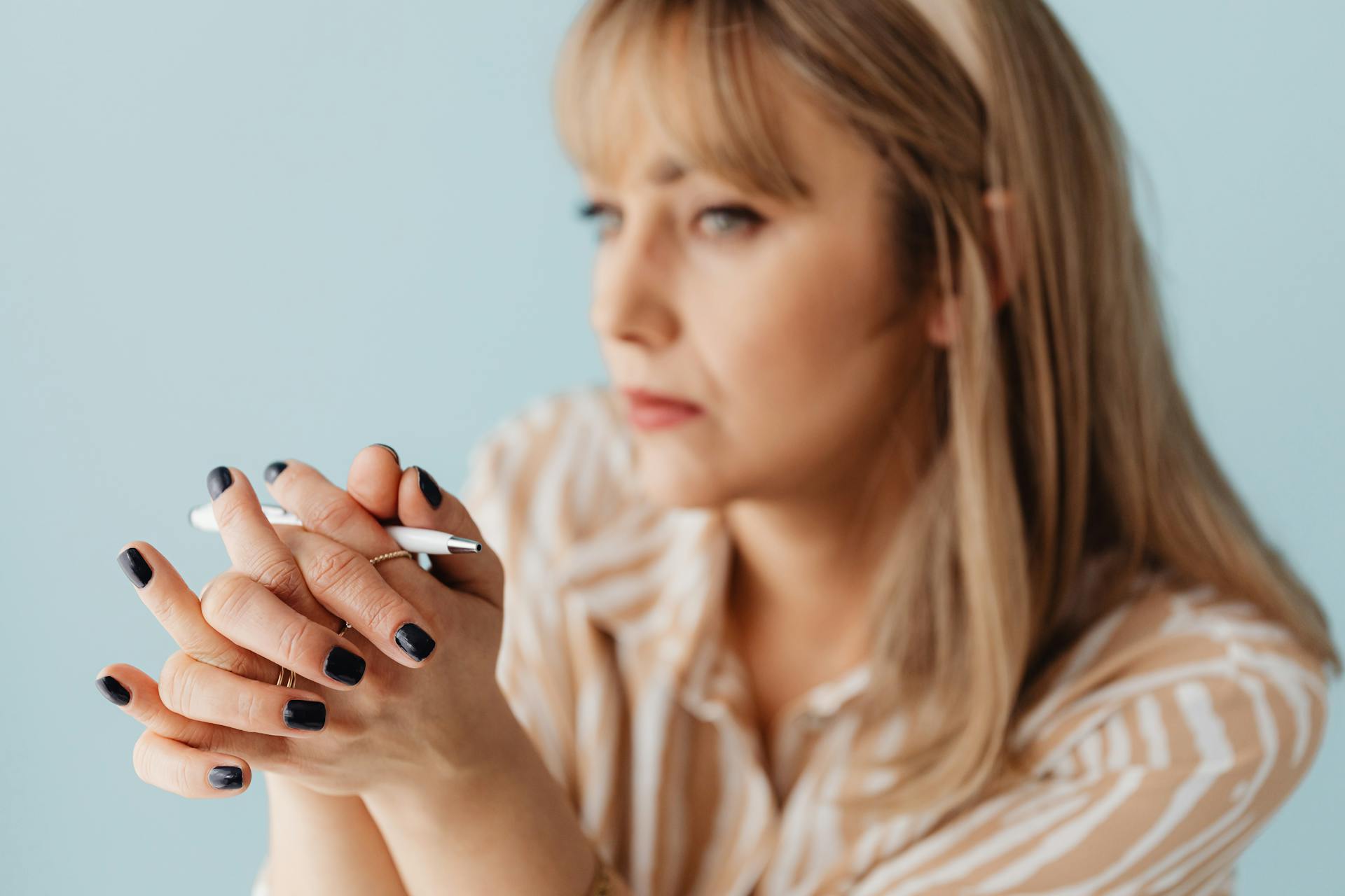 Una mujer sujetando un bolígrafo blanco | Fuente: Pexels