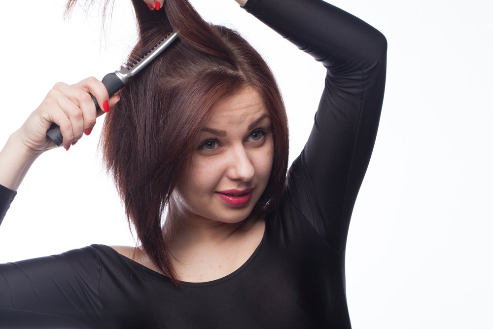 Mujer planchándose en cabello. | Foto: Shutterstock