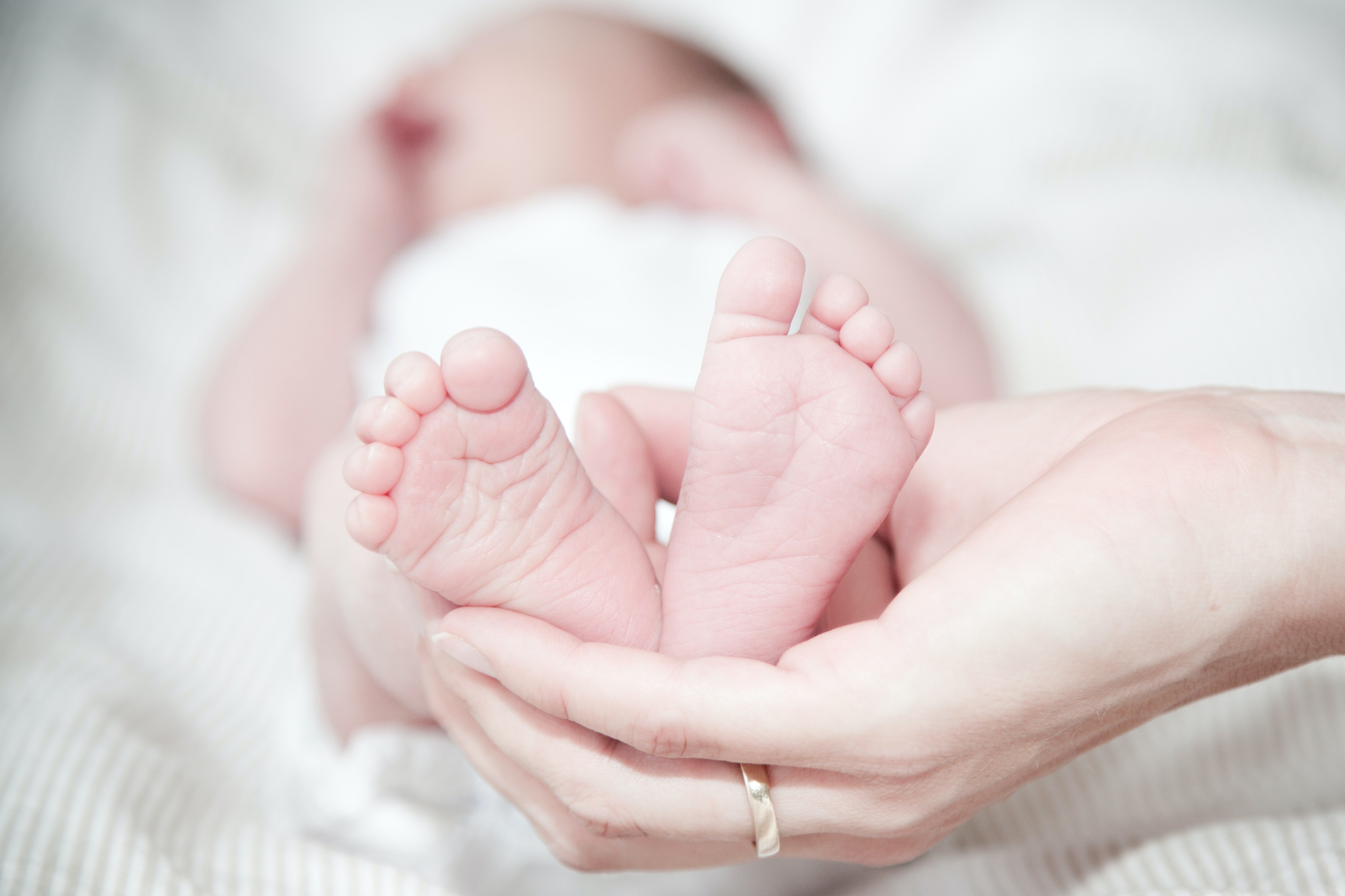 Hombre tomando los pequeños pies de una bebé en su mano. | Foto: Pexels