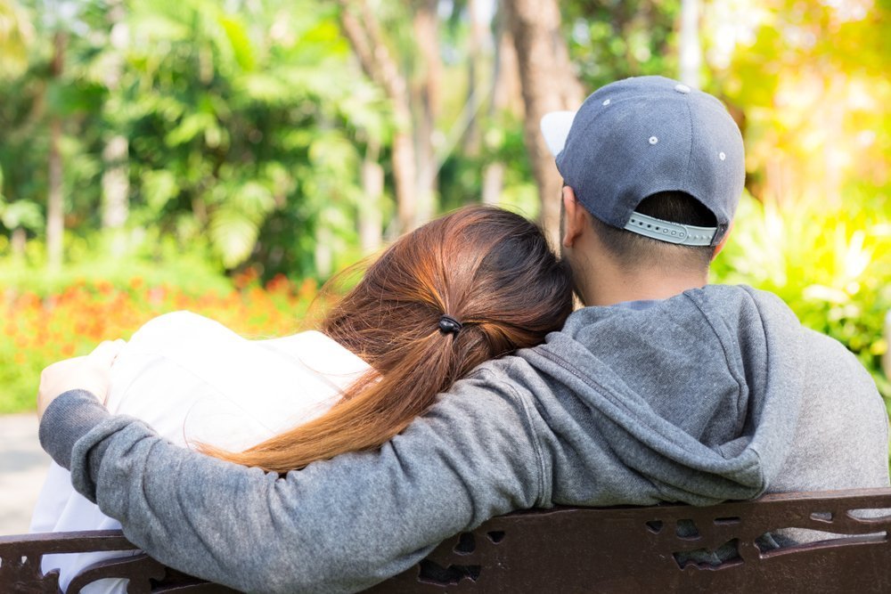 Encantadora pareja se sienta en el parque. Encantadora novia apoya su cabeza en el hombro de su novio. | Foto: Shutterstock