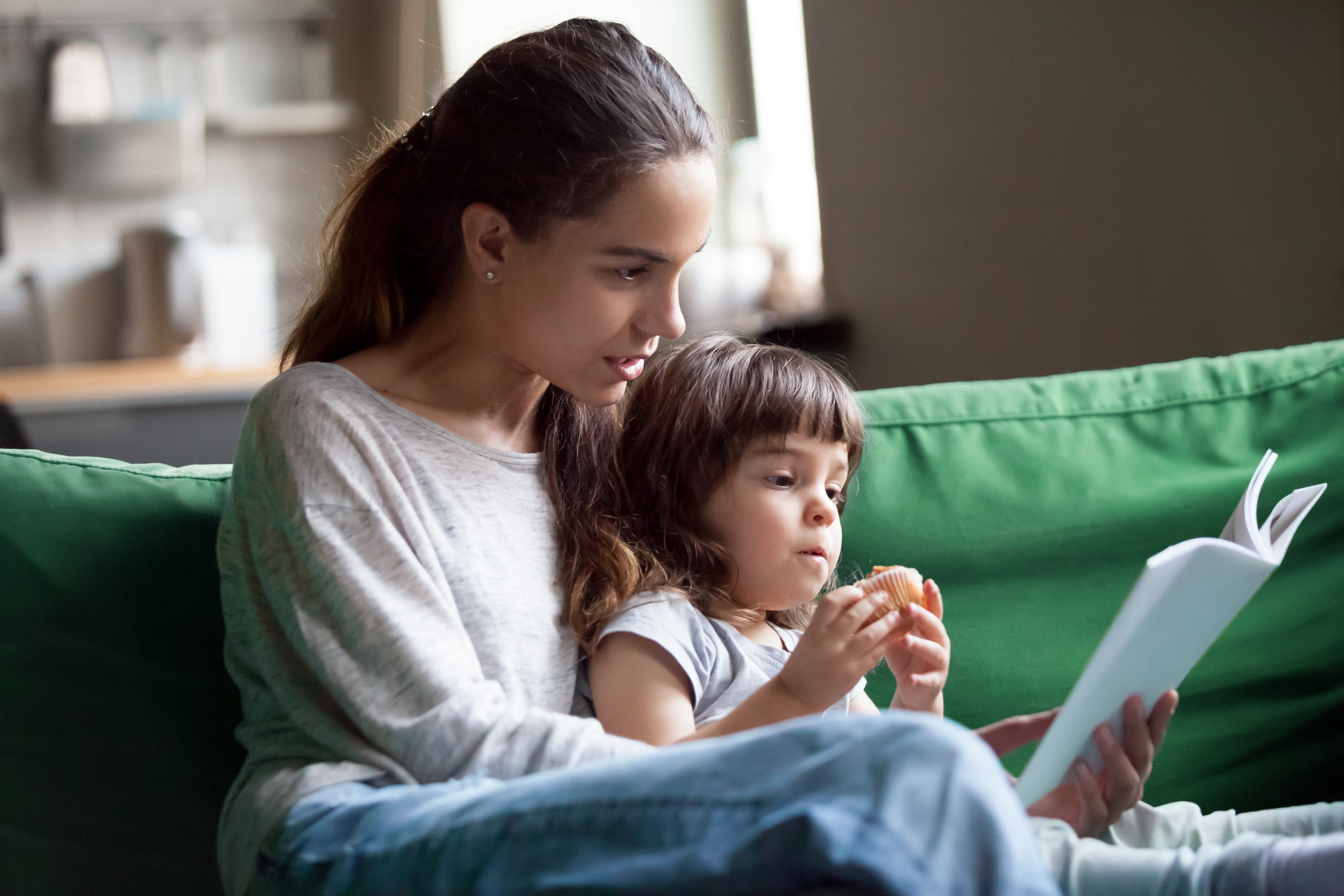 Una joven leyendo un libro con una niña | Fuente: Shutterstock