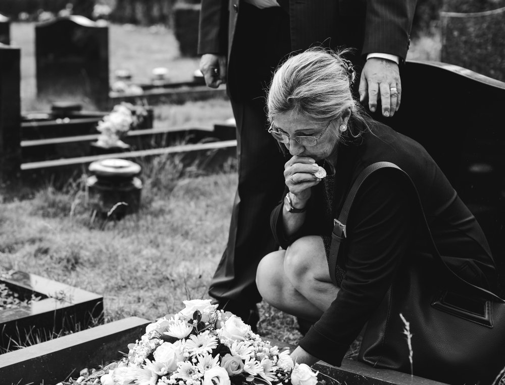 Anciana colocando flores sobre una tumba. I Foto: Shutterstock.