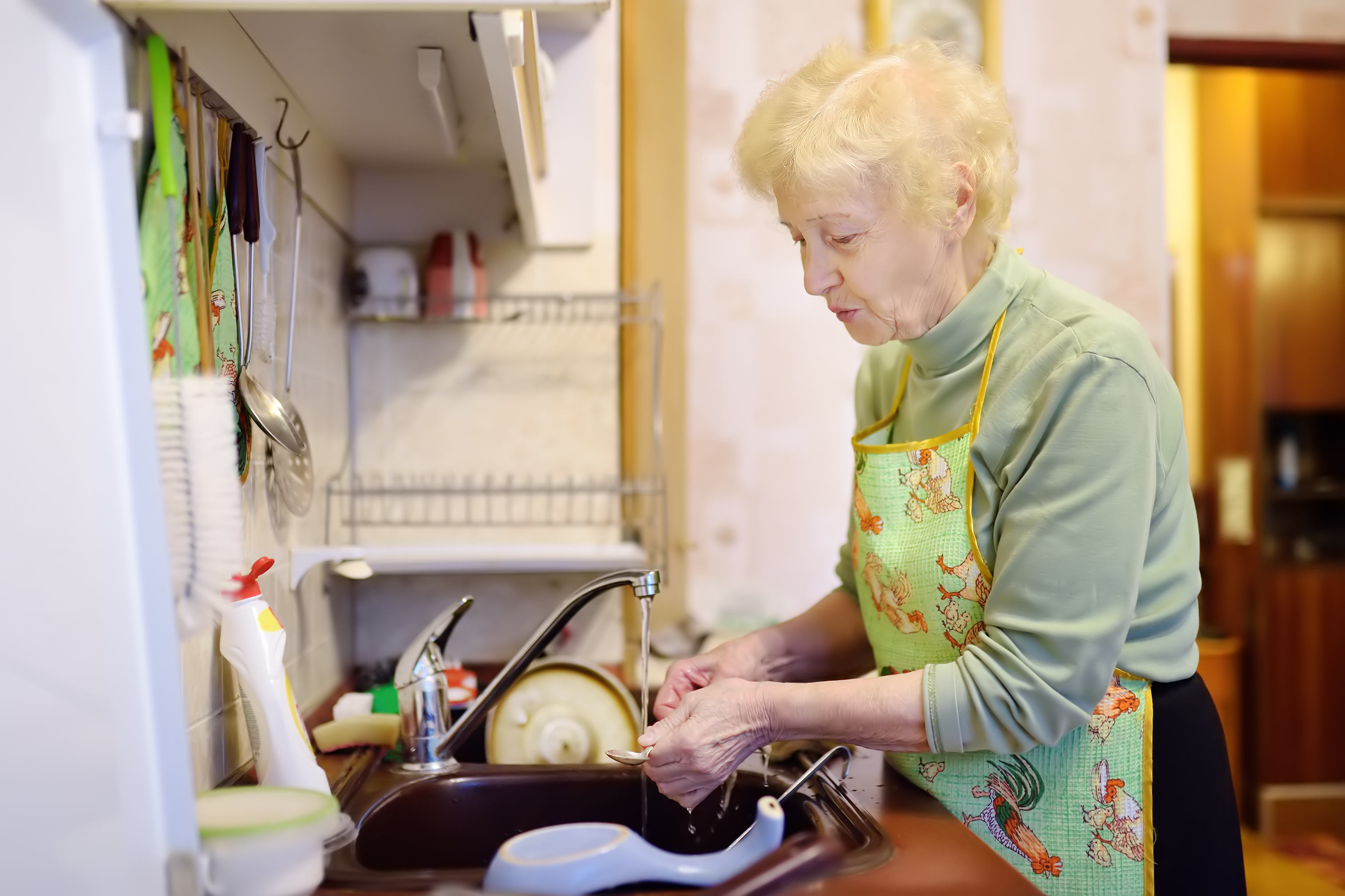 Una anciana lava los platos en la cocina | Foto: Shutterstock