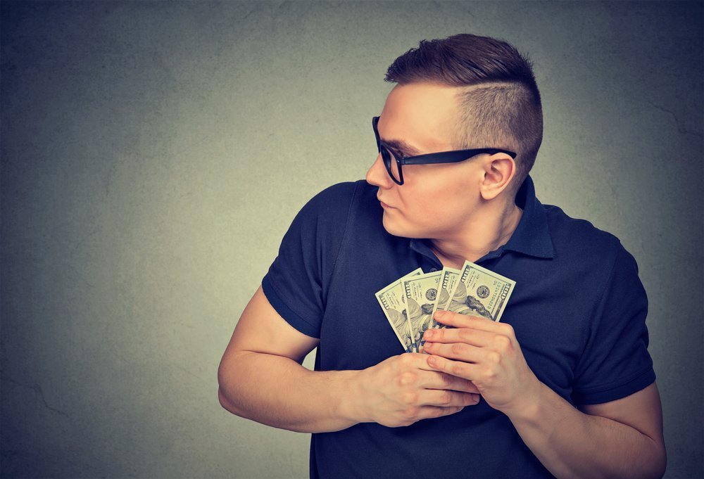 Hombre egoísta agarrando dinero | Foto: Shutterstock