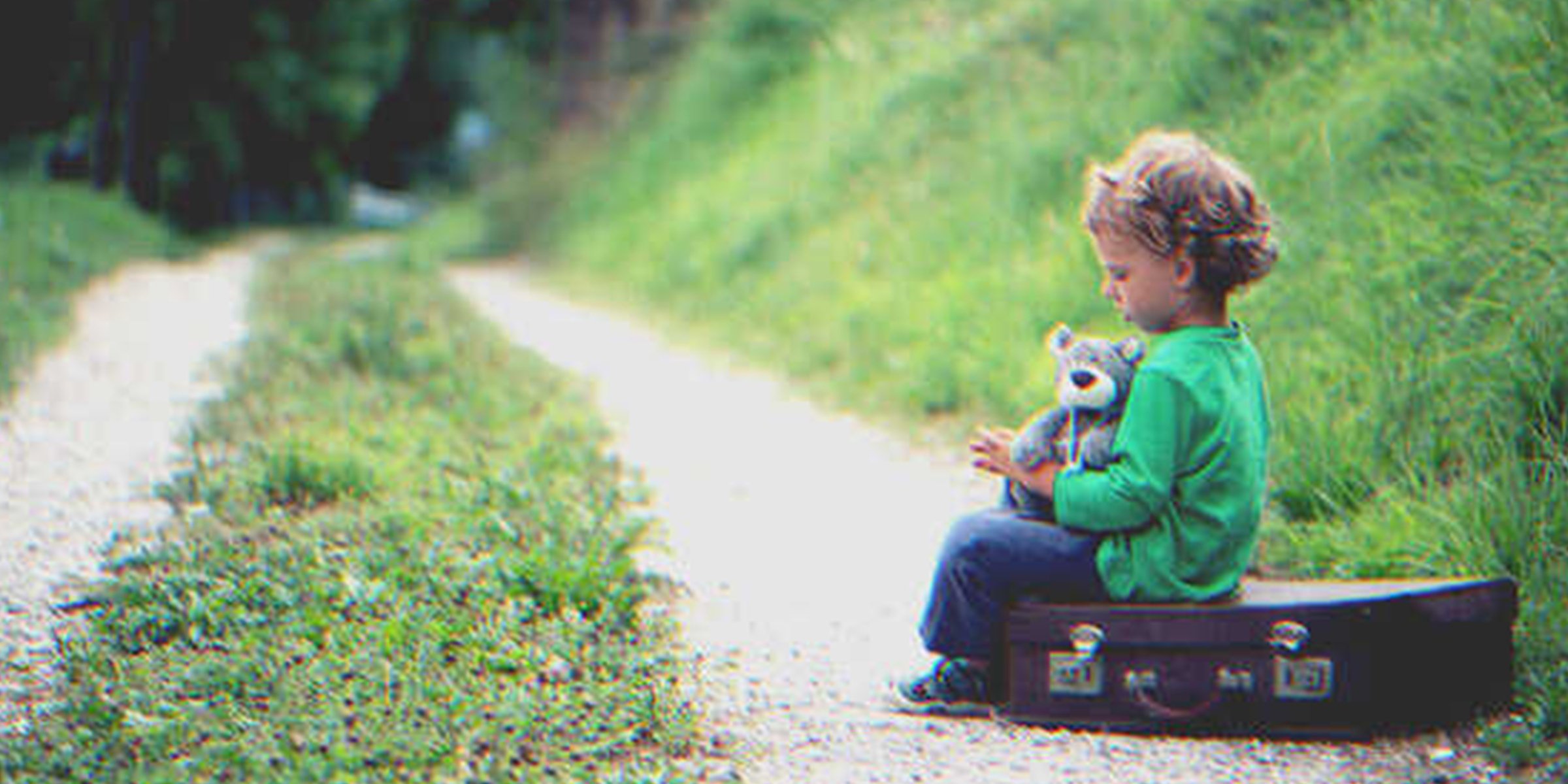 Un niño sentado sobre una valija al costado de un camino | Foto. Getty Images