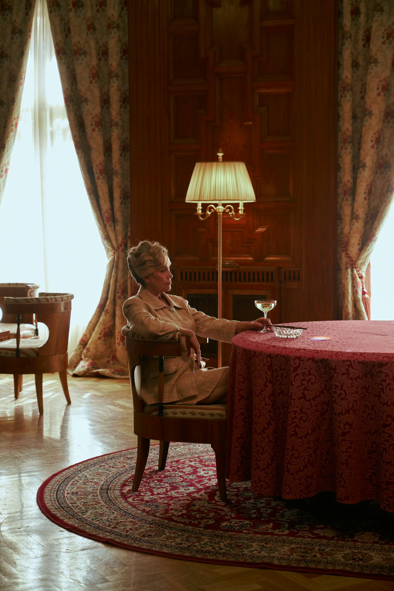 Una elegante mujer mayor sentada a una mesa y con una copa en la mano | Fuente: Pexels