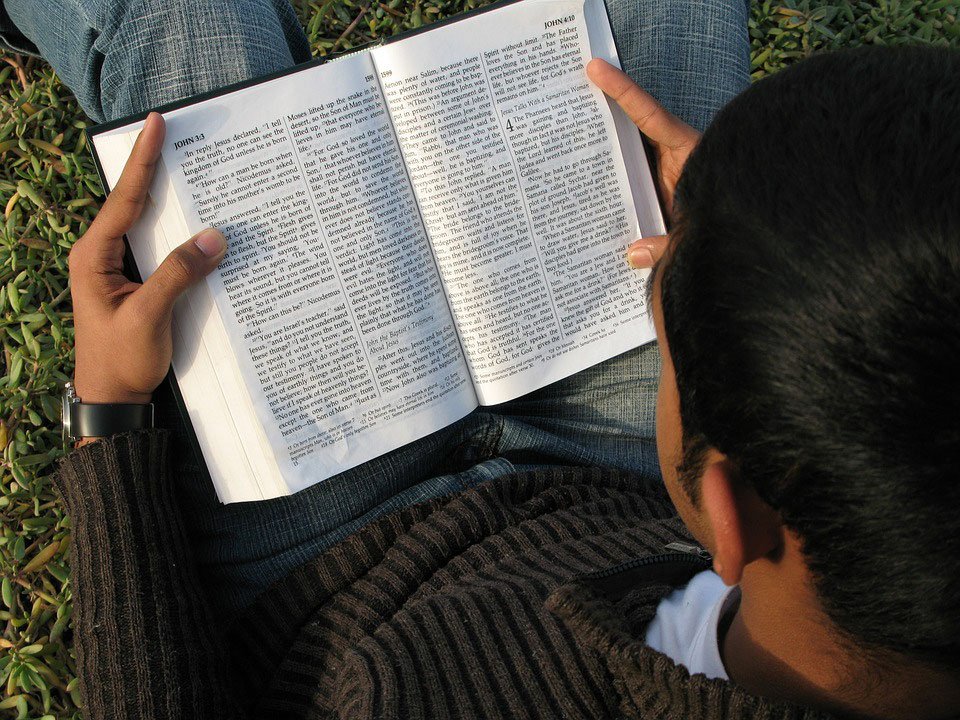 Joven sentado leyendo la Biblia. | Foto: PxHere