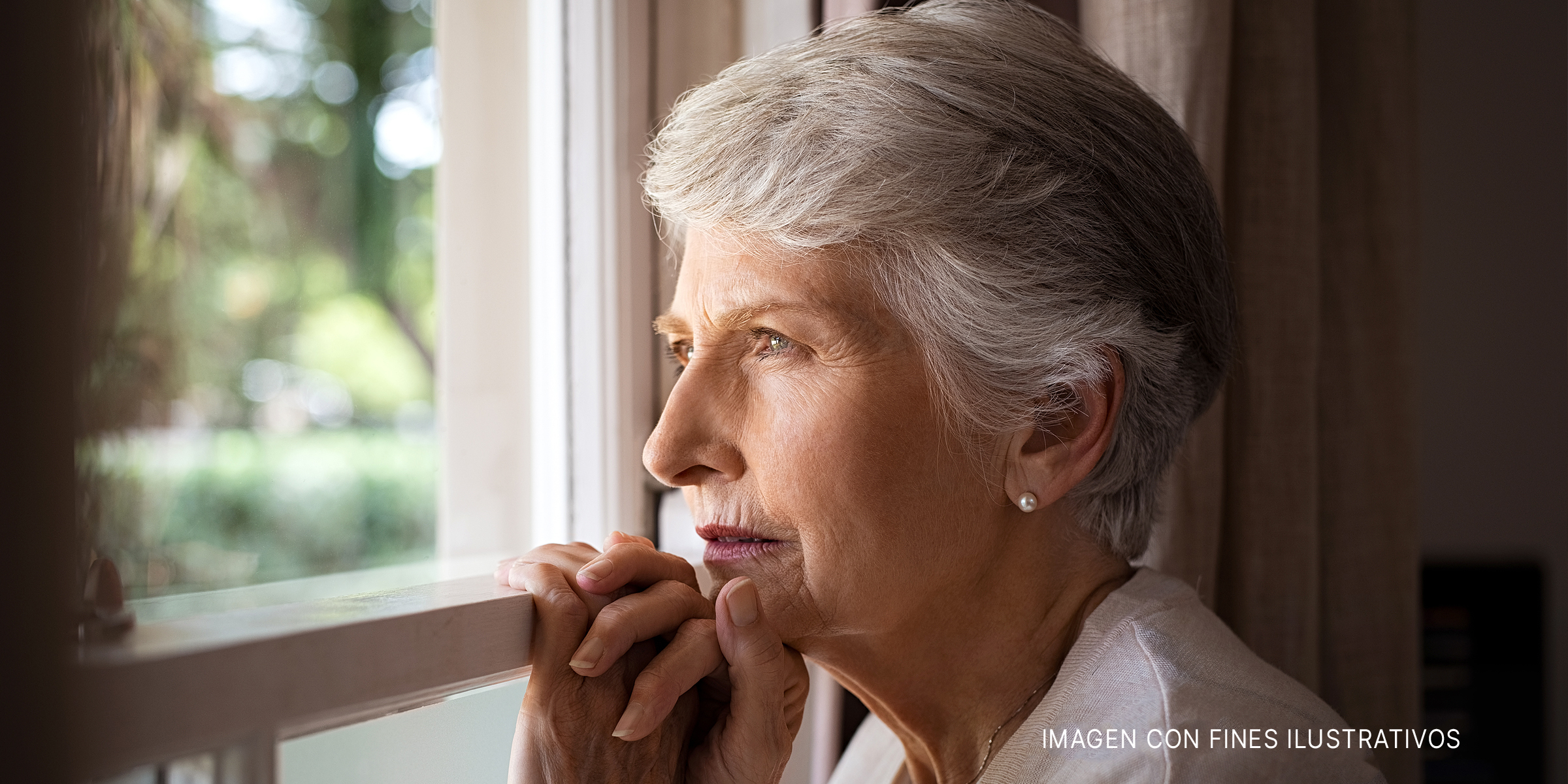 Mujer mayor mirando por una ventana | Fuente: Getty Images