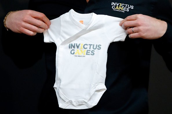 El Príncipe Harry, Duque de Sussex, con ropa de bebé con el texto "Invictus Games" para su hijo recién nacido, Archie. | Fuente: Getty Images