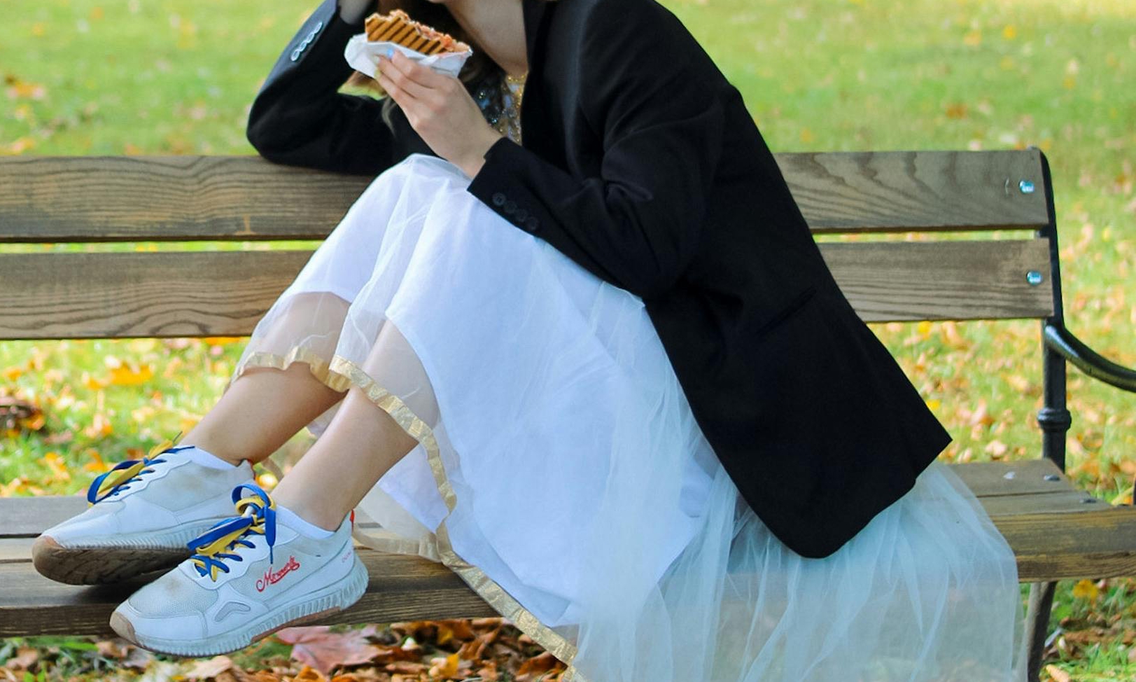 Una mujer comiendo un bocadillo en un banco del parque | Fuente: Pexels