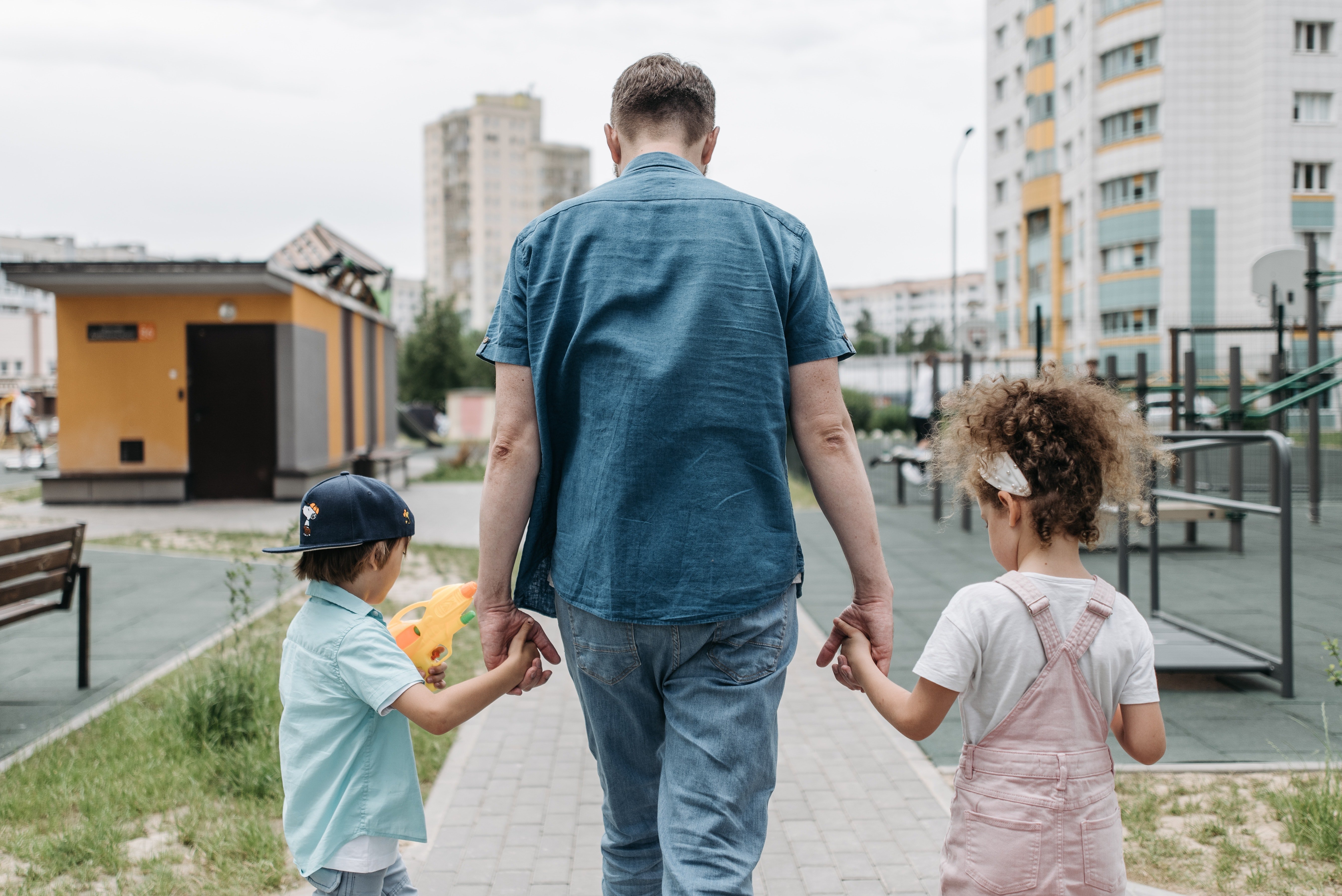 Un hombre camina con un niño y una niña de la mano. | Foto: Pexels