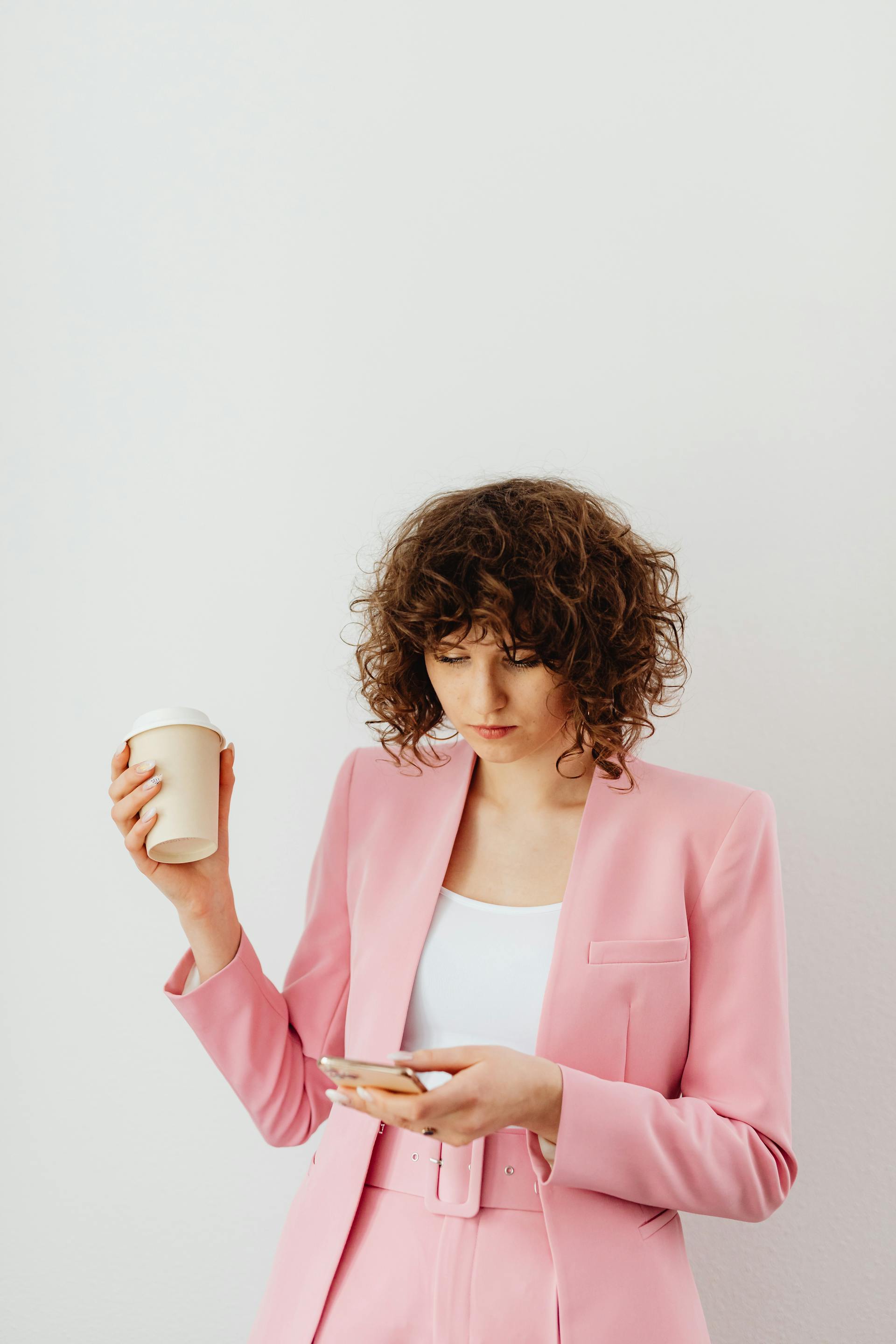 Una mujer decidida con un café y un teléfono en la mano | Fuente: Pexels