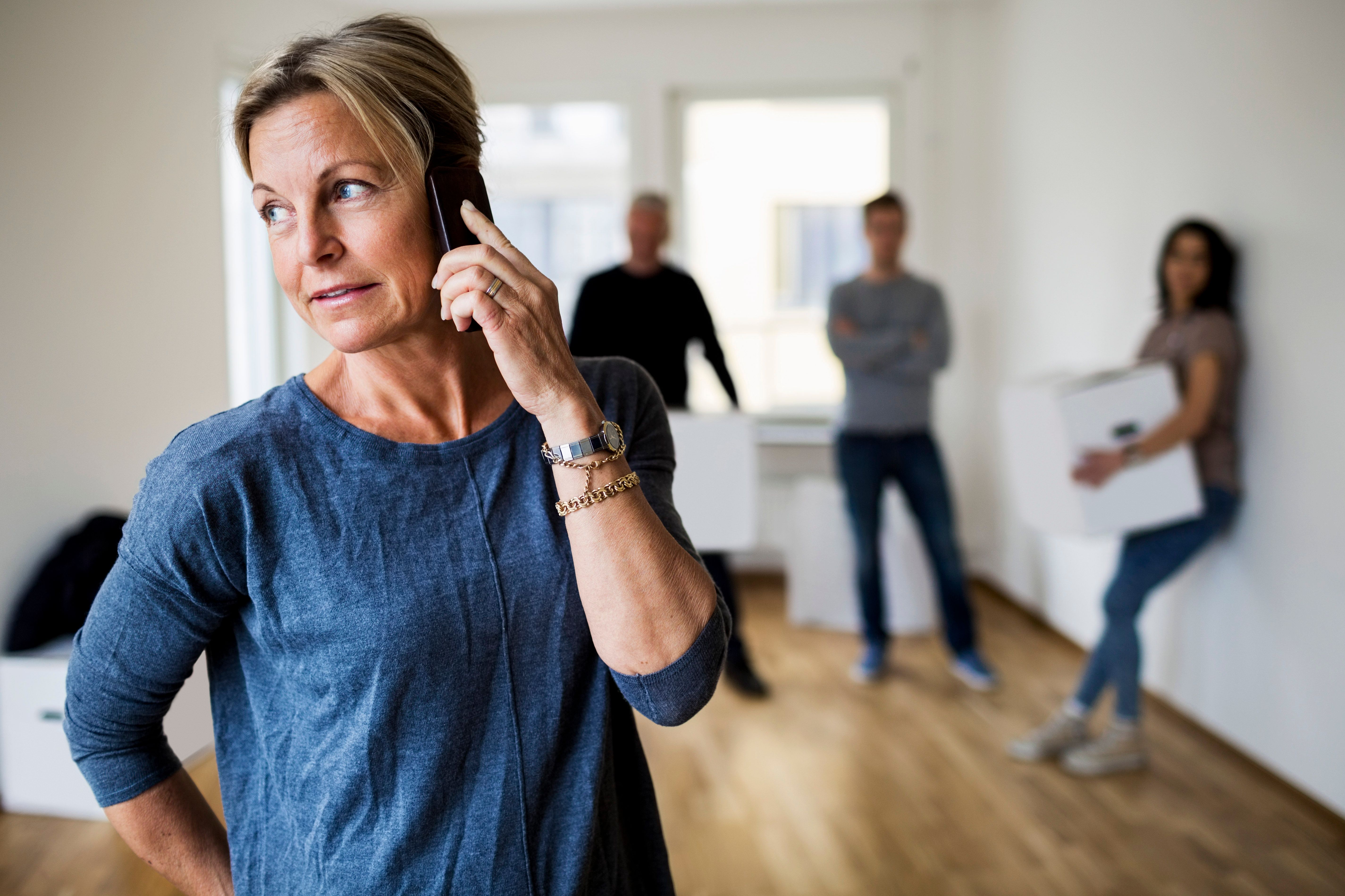 Mujer hablando por teléfono con personas al fondo | Foto: Getty Images