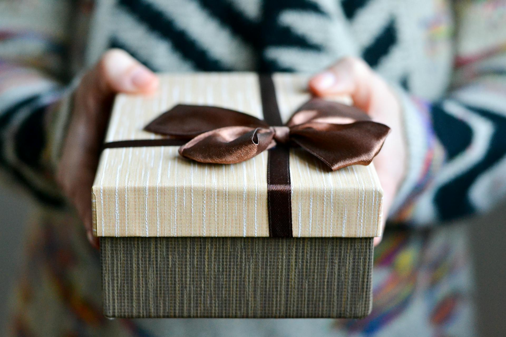 Primer plano de una persona que sostiene una caja de regalo con un lazo marrón | Fuente: Pexels