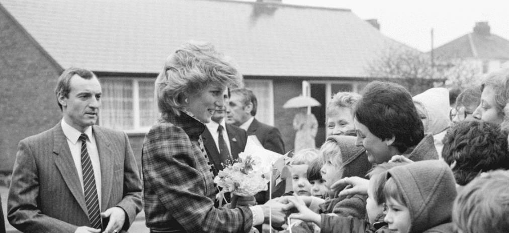 La princesa Diana saludando a unos niños con su guardaespaldas, Barry Mannakee, detrás de ella en Mid Glamorgan, Gales, el 29 de enero de 1985. | Foto: Getty Images