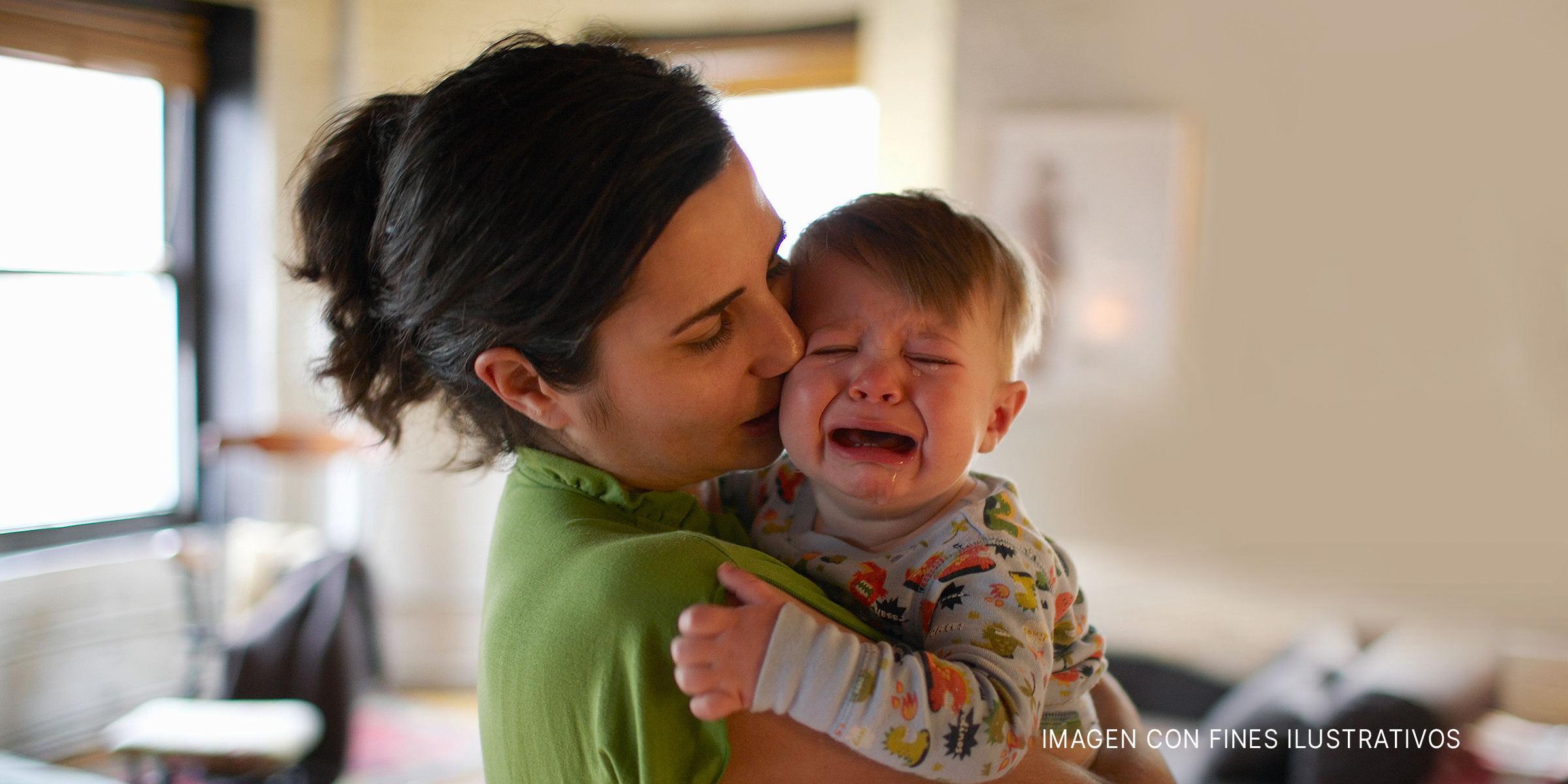 Una madre sostiene y besa a su bebé que llora | Foto: Getty Images