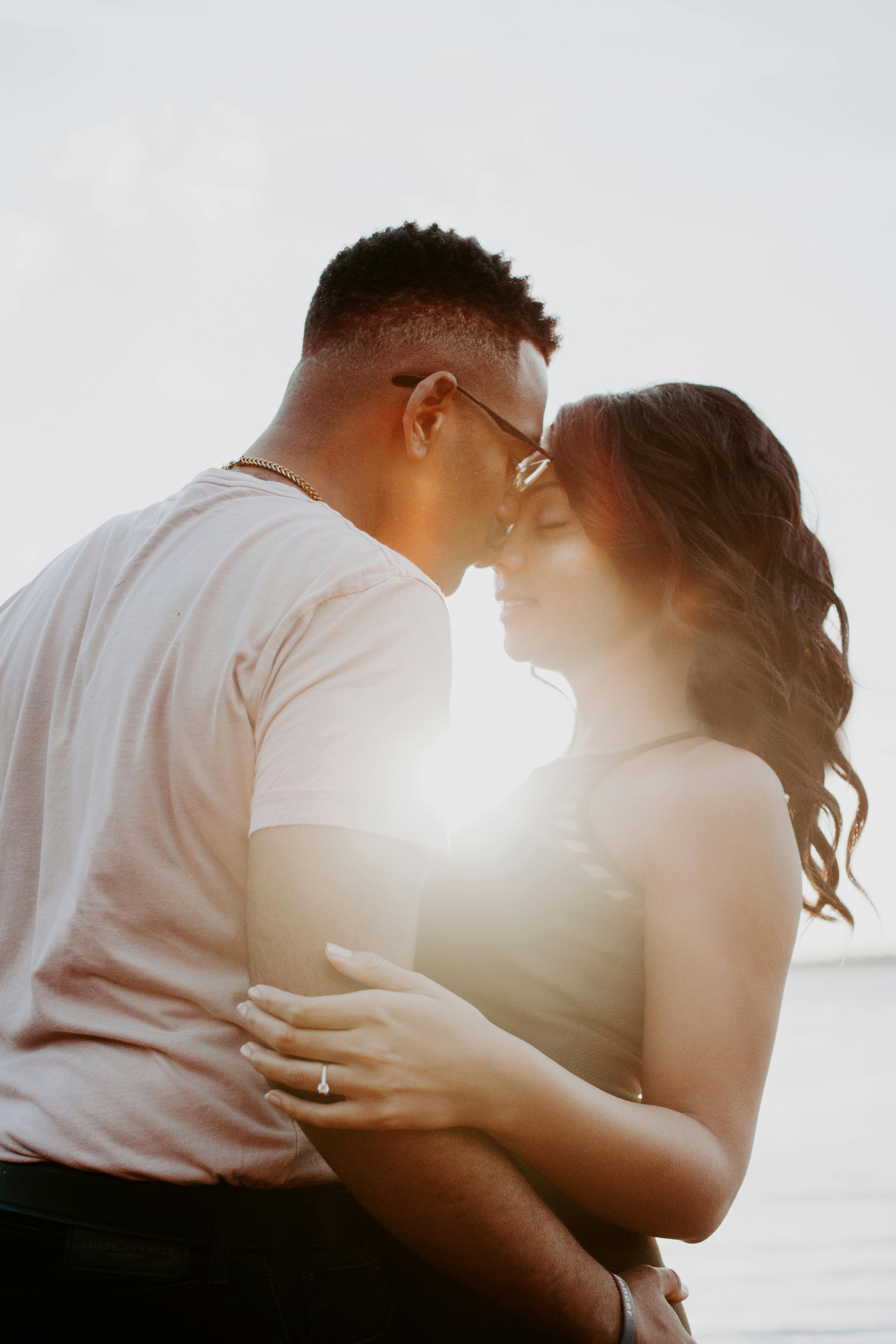 Pareja compartiendo un beso en medio de una puesta de sol | Foto: Pexels