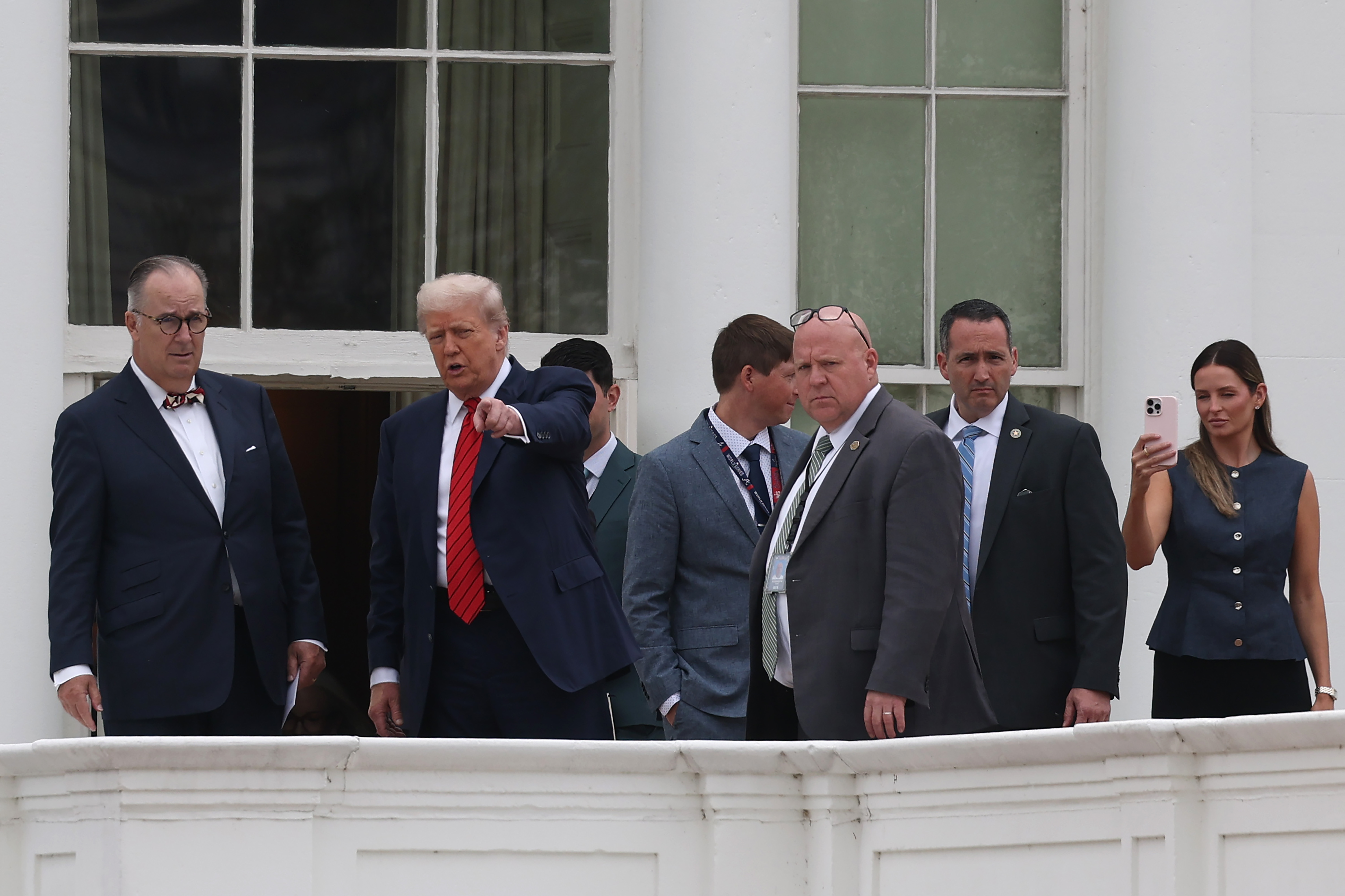 Con un gesto asertivo, Donald Trump habla con su personal y con el arquitecto James C. McCrery en la azotea de la Casa Blanca en Washington, D.C., convirtiendo su inesperada visita en un momento memorable.
