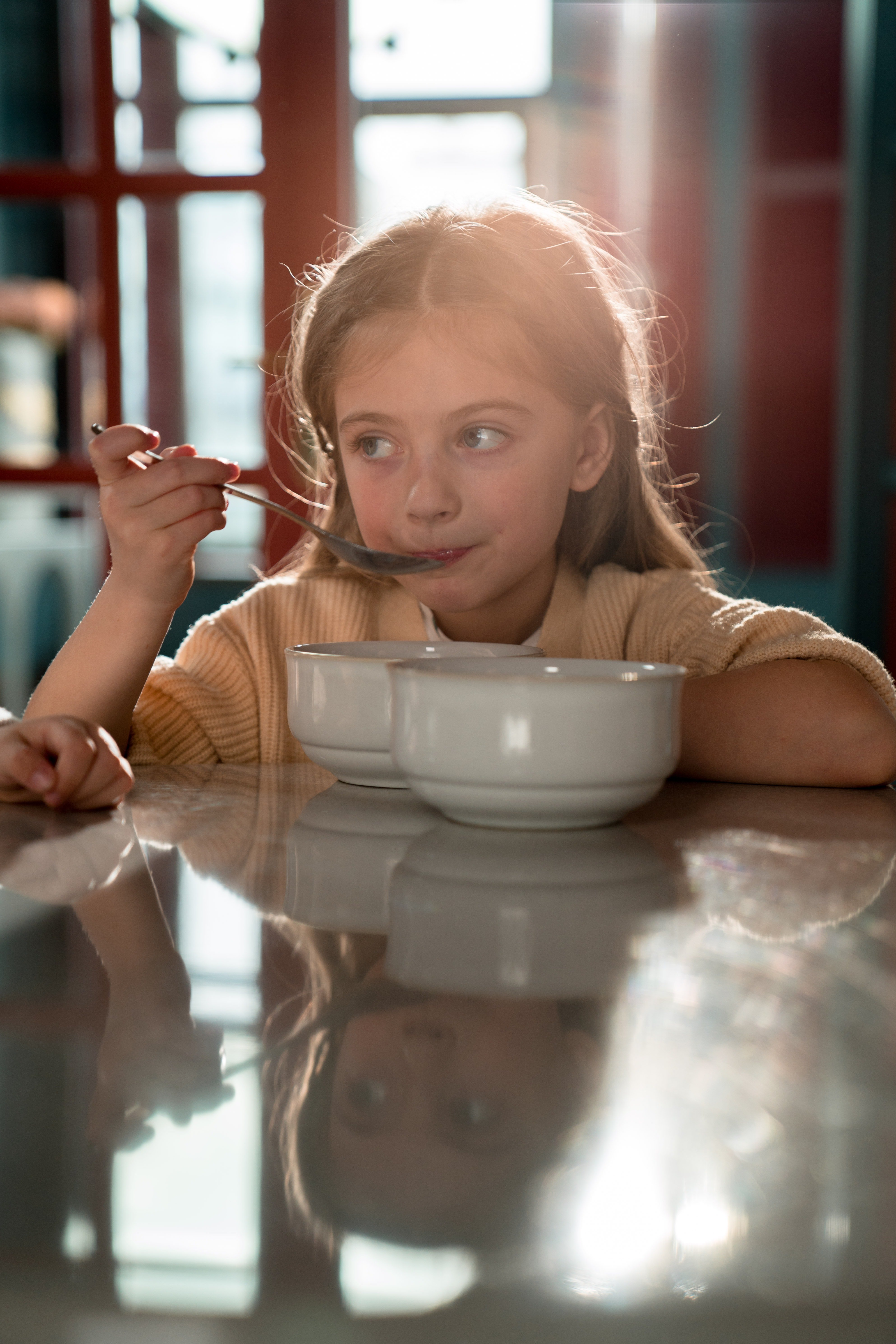 Una niña sentada frente a una mesa comiendo. | Foto: Pexels