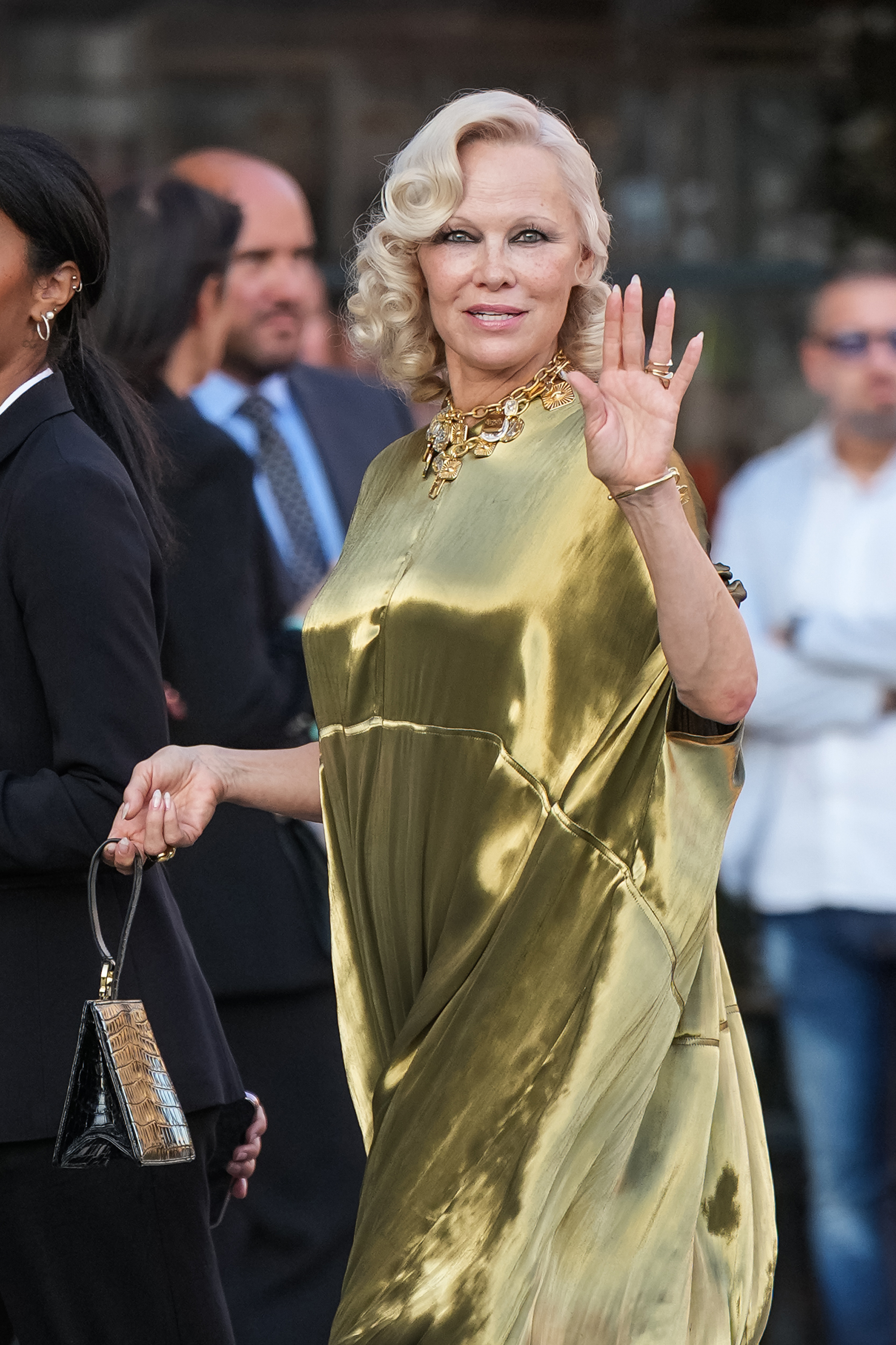 Anderson sonríe y saluda a los curiosos al llegar, lo que permite apreciar mejor sus rizos perfectos, su collar de oro y su vestido reluciente. | Fuente: Getty Images