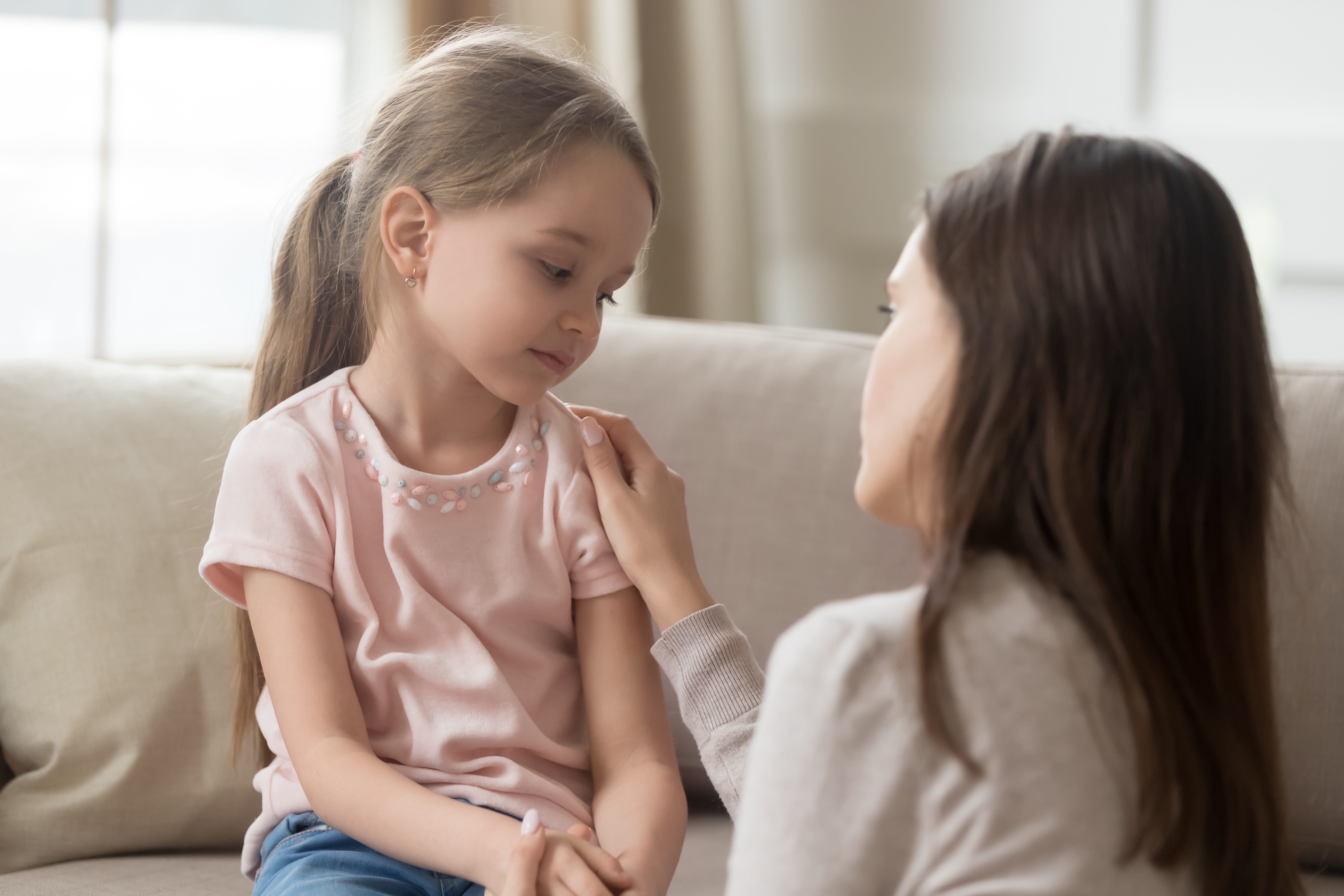 Una madre preocupada consuela a su niña triste. | Foto: Shutterstock