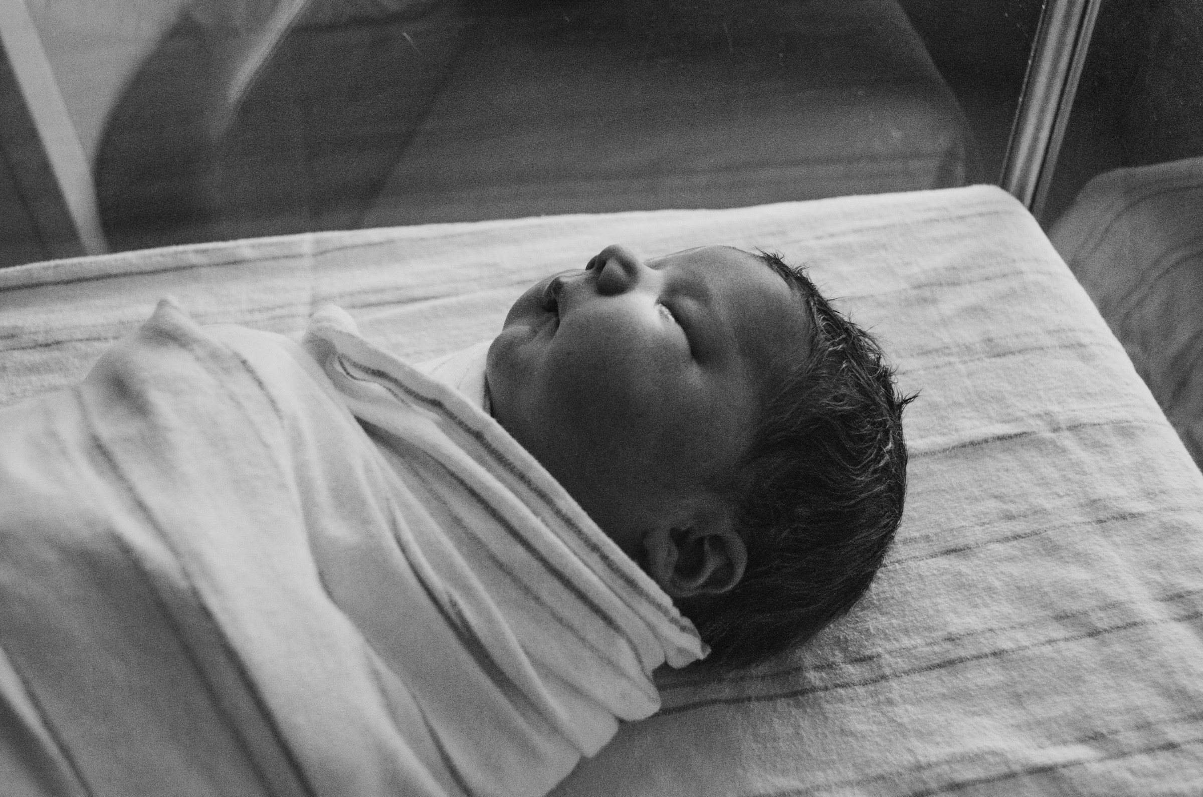 Foto en escala de grises de un recién nacido envuelto en una tela | Fuente: Unsplash