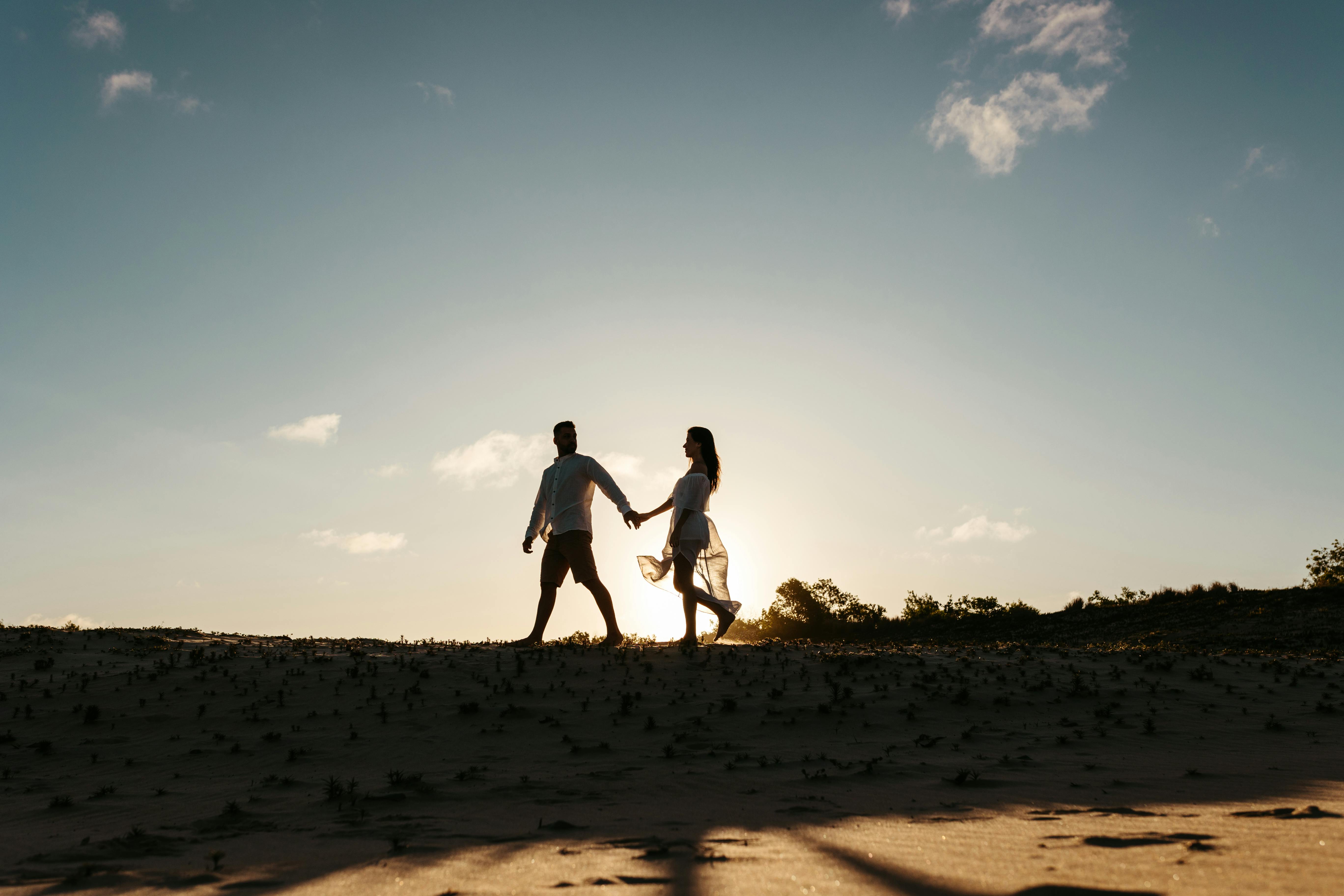 Hombre y mujer caminando de la mano al aire libre | Fuente: Pexels