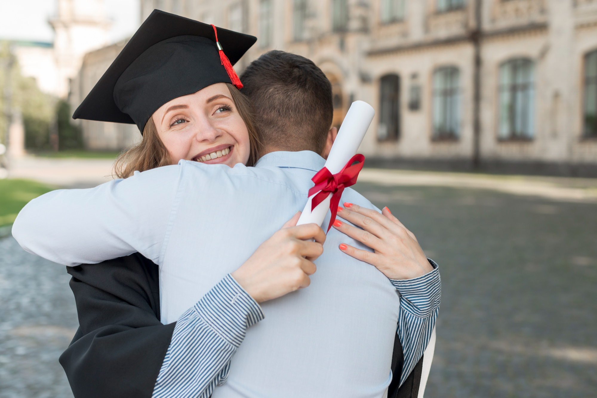 Una graduada universitaria feliz siendo abrazada por un hombre | Fuente: Pexels