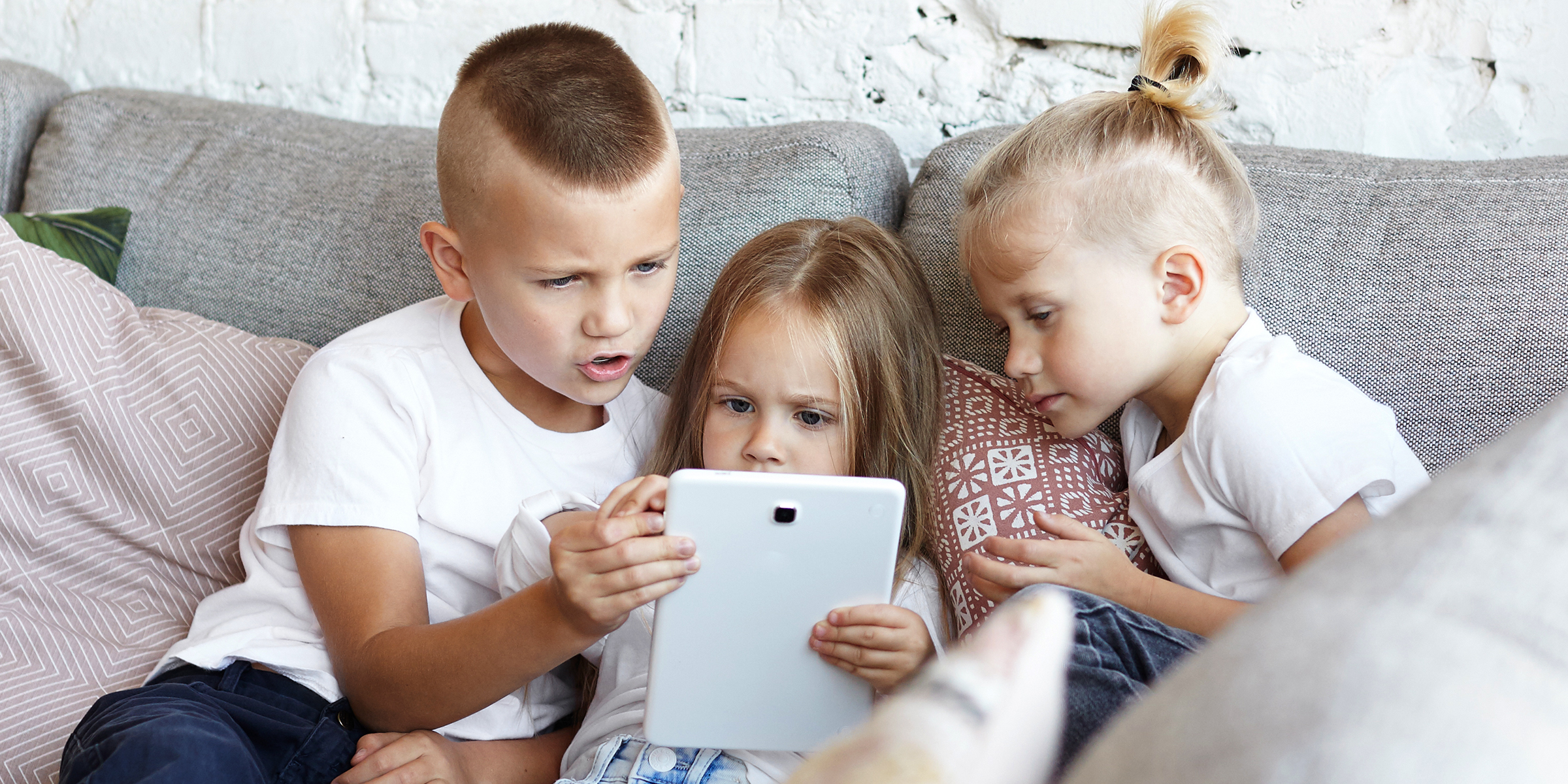 Tres niños sentados en un sofá | Fuente: Shutterstock