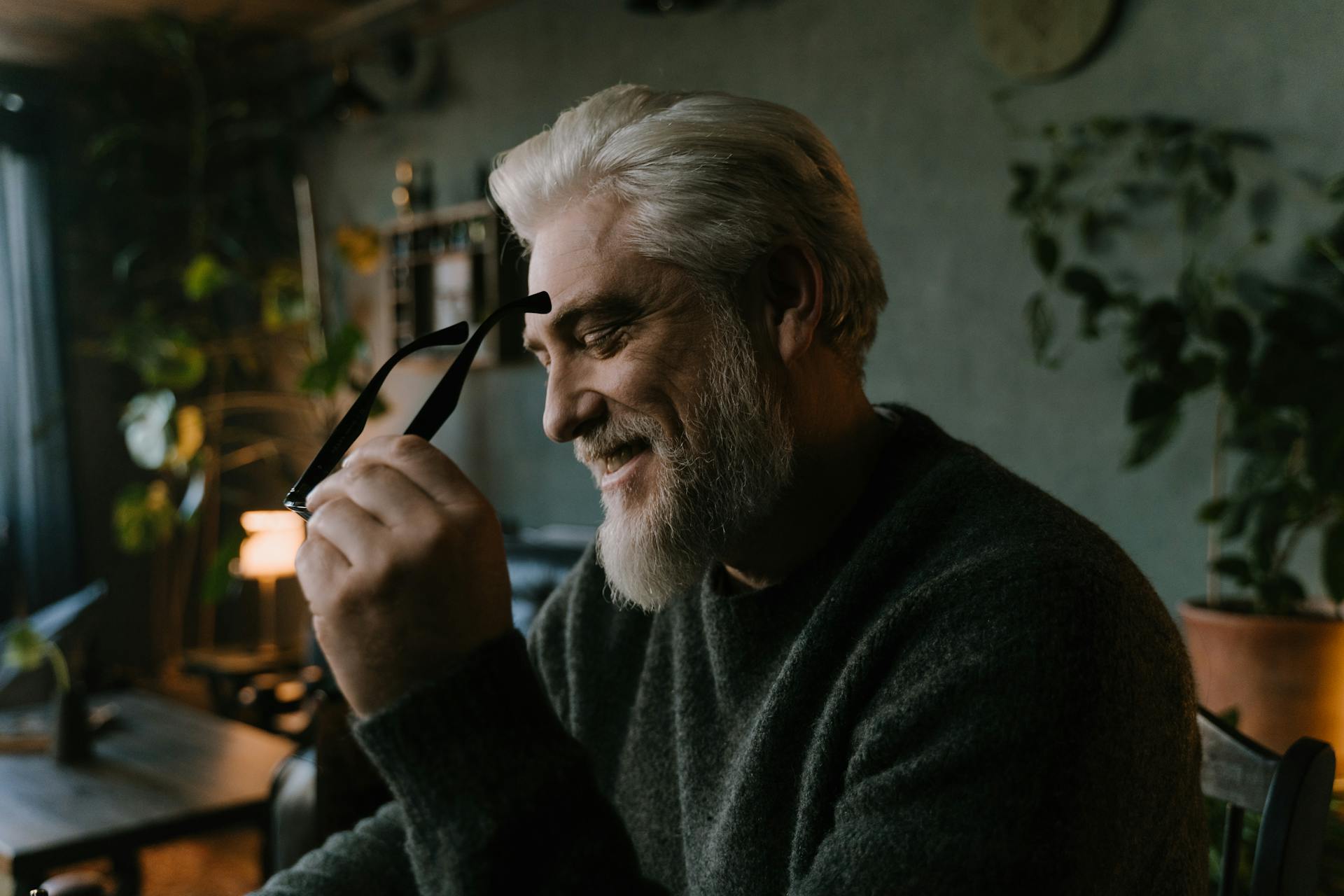 Un hombre mayor sosteniendo sus gafas y riendo | Fuente: Pexels