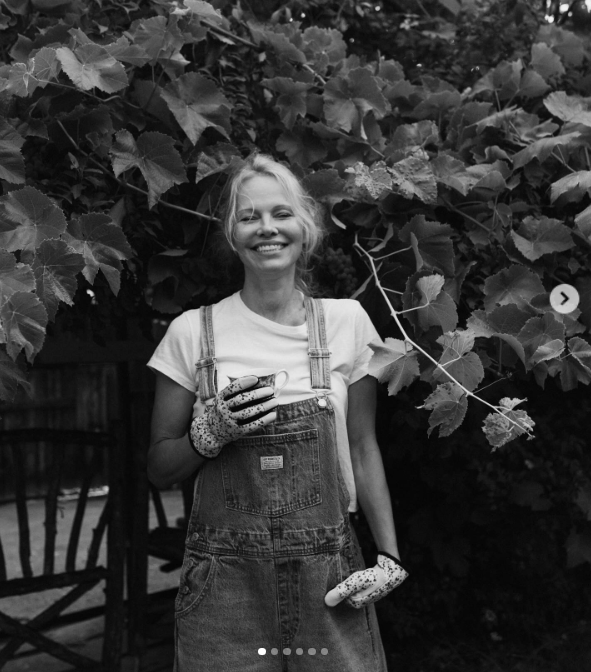 En un luminoso retrato en blanco y negro, Pamela Anderson nos regala una sonrisa radiante y sin maquillaje frente a una densa pared de hojas de parra en Arcady. Vestida con un mono vaquero, guantes de jardinería y con una pequeña taza de té en la mano, irradia pura alegría mientras habla de "Pamela's Cooking with Love", y describe el programa de la isla de Vancouver como un auténtico proyecto de ensueño que combina su floreciente jardín con el talento culinario internacional. | Fuente: Instagram/pamelaanderson