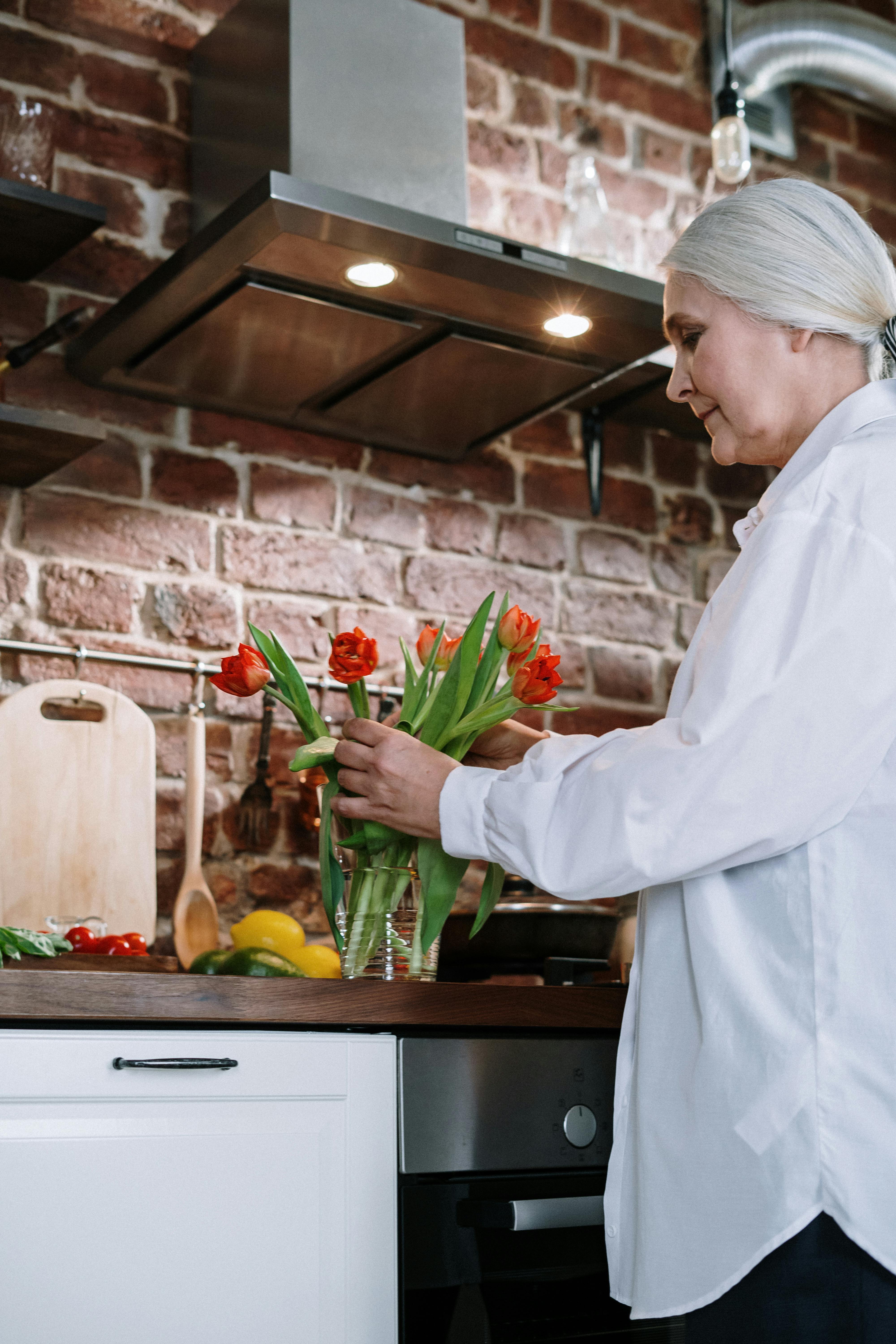 Mujer arreglando flores en un jarrón | Fuente: Pexels