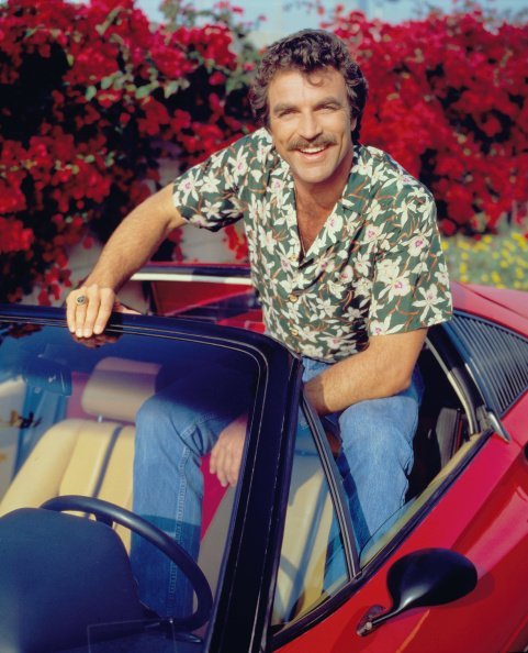 El actor Tom Selleck interpreta a Thomas Sullivan Magnum en la serie de televisión de CBS "Magnum, P.I." Lleva un Ferrari 308 rojo y una camisa con estampado floral hawaiano. Imagen del 1 de enero de 1984. | Foto: Getty Images