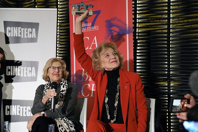 Marisa Paredes y la alcaldesa de Madrid, Manuel Carmena, en los premios “Puerta de Toledo” en el marco de la 37ª Semana de Cine Español en Carabanchel, 17 de enero de 2019. | Imagen: Wikimedia Commons