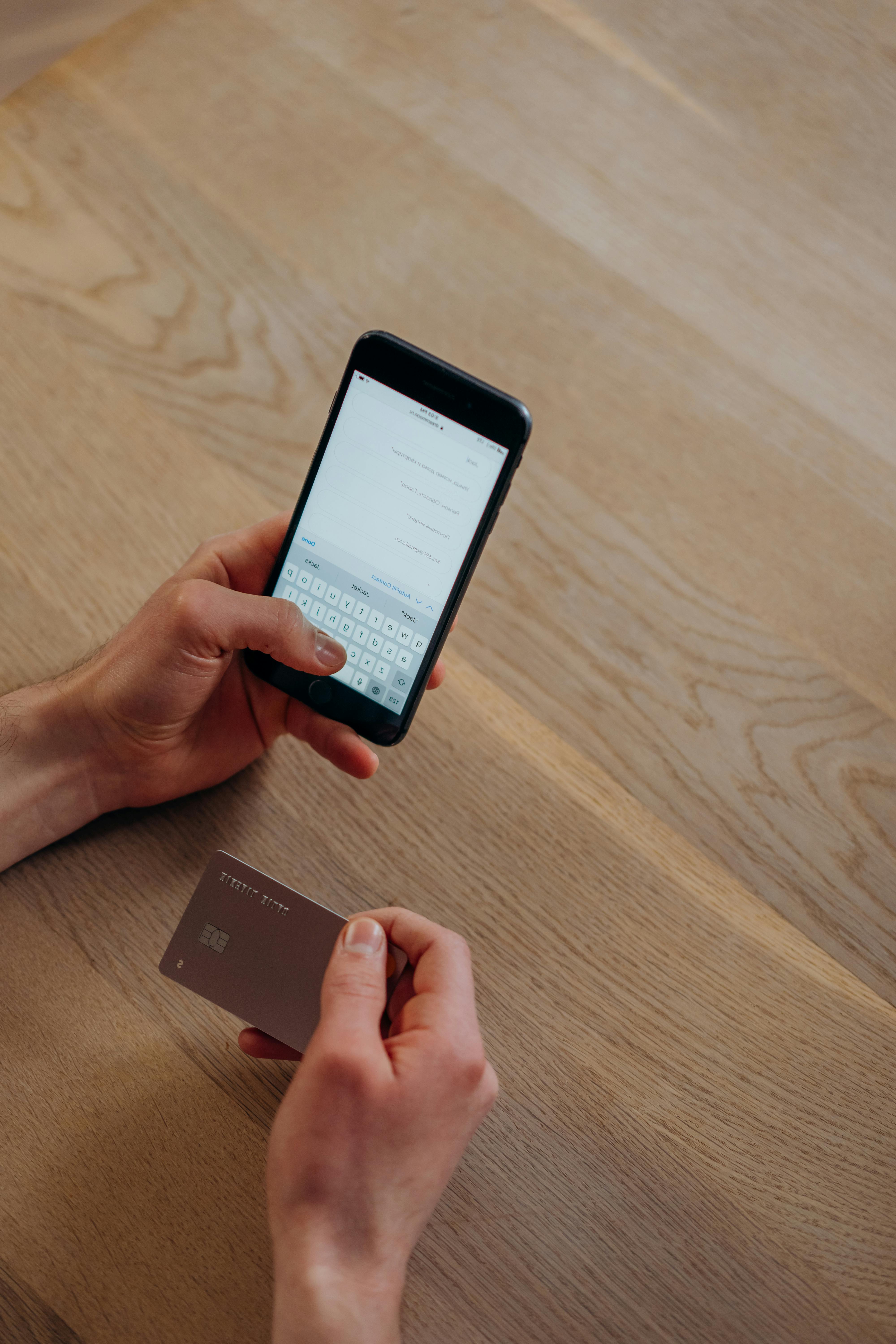 Una persona envía un mensaje de texto mientras sostiene una tarjeta de crédito | Foto: Pexels