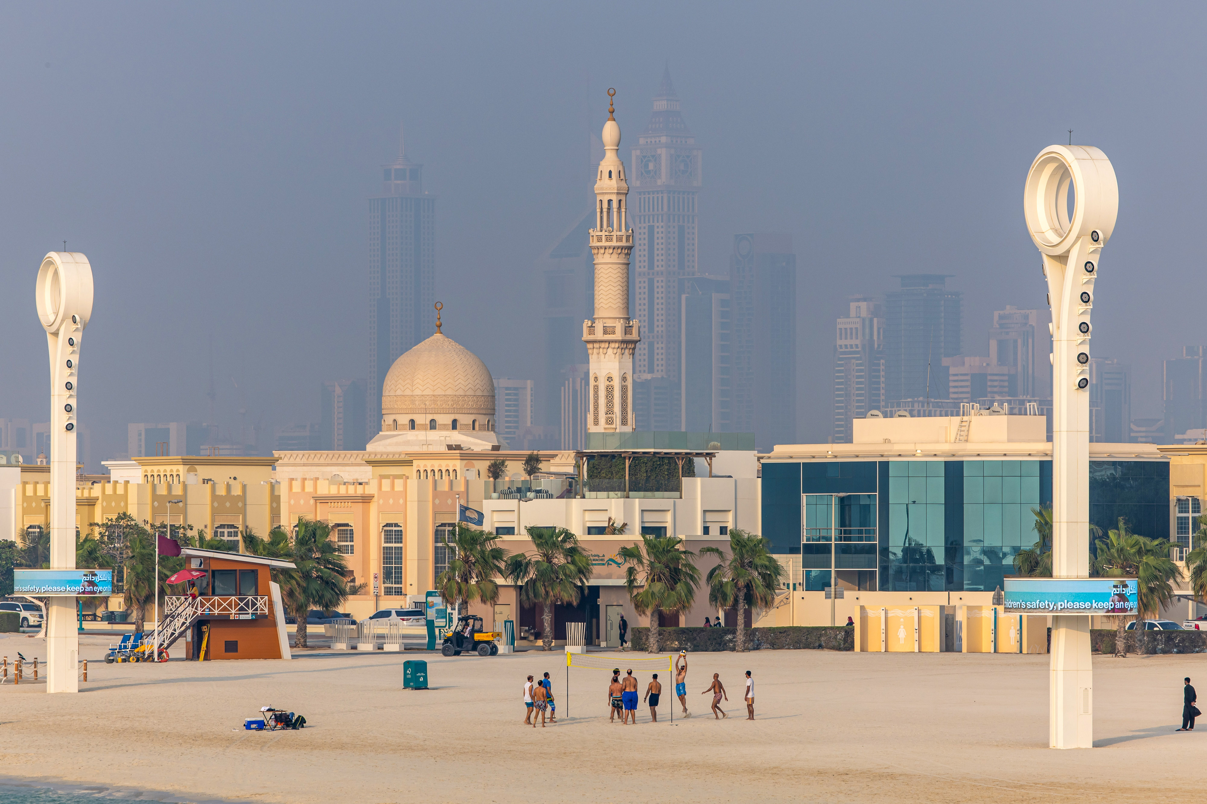 Unos playeros juegan al voleibol, con el telón de fondo de propiedades residenciales y comerciales en el distrito de Jumeirah Beach de Dubai, Emiratos Árabes Unidos, el 25 de agosto de 2023. | Foto: Getty Images