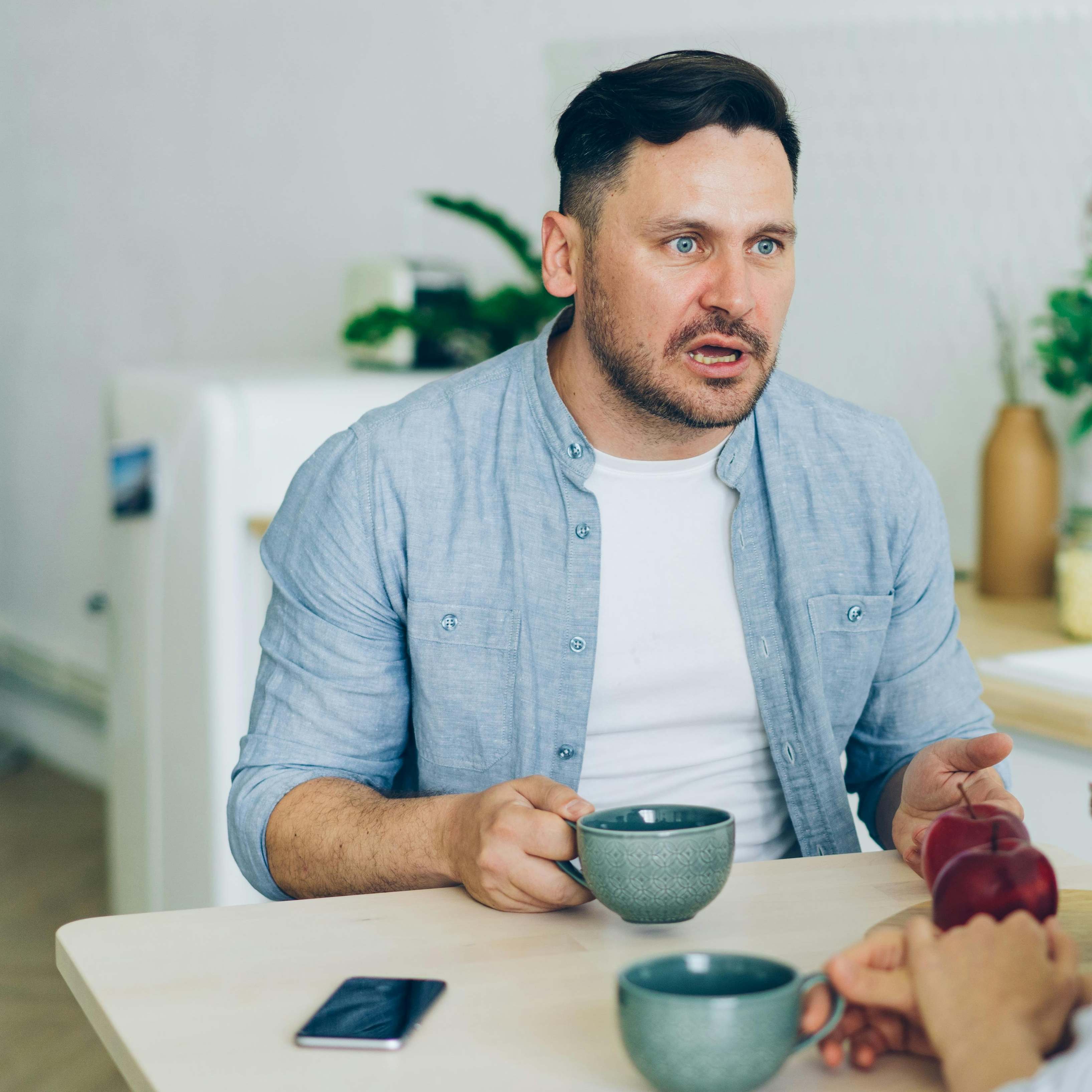 Un hombre sentado frente a la mesa de alguien, reaccionando con sorpresa | Fuente: Pexels