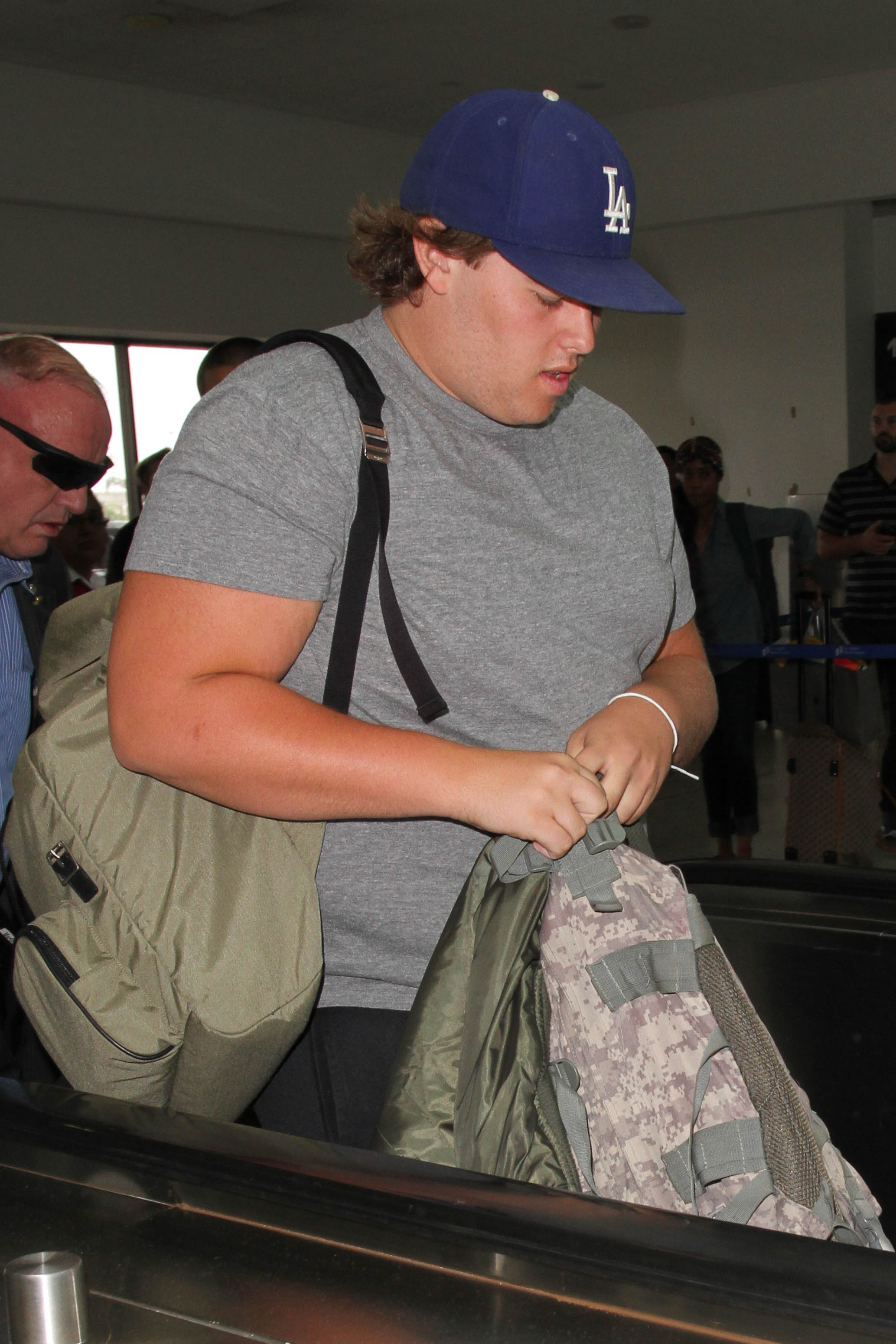 En otra instantánea del mismo día, Christopher sale de la terminal con ropa deportiva informal, que incluye pantalones cortos negros y zapatillas grises. La gorra y el peinado suelto contribuyen a su aspecto relajado mientras se mueve con paso decidido.