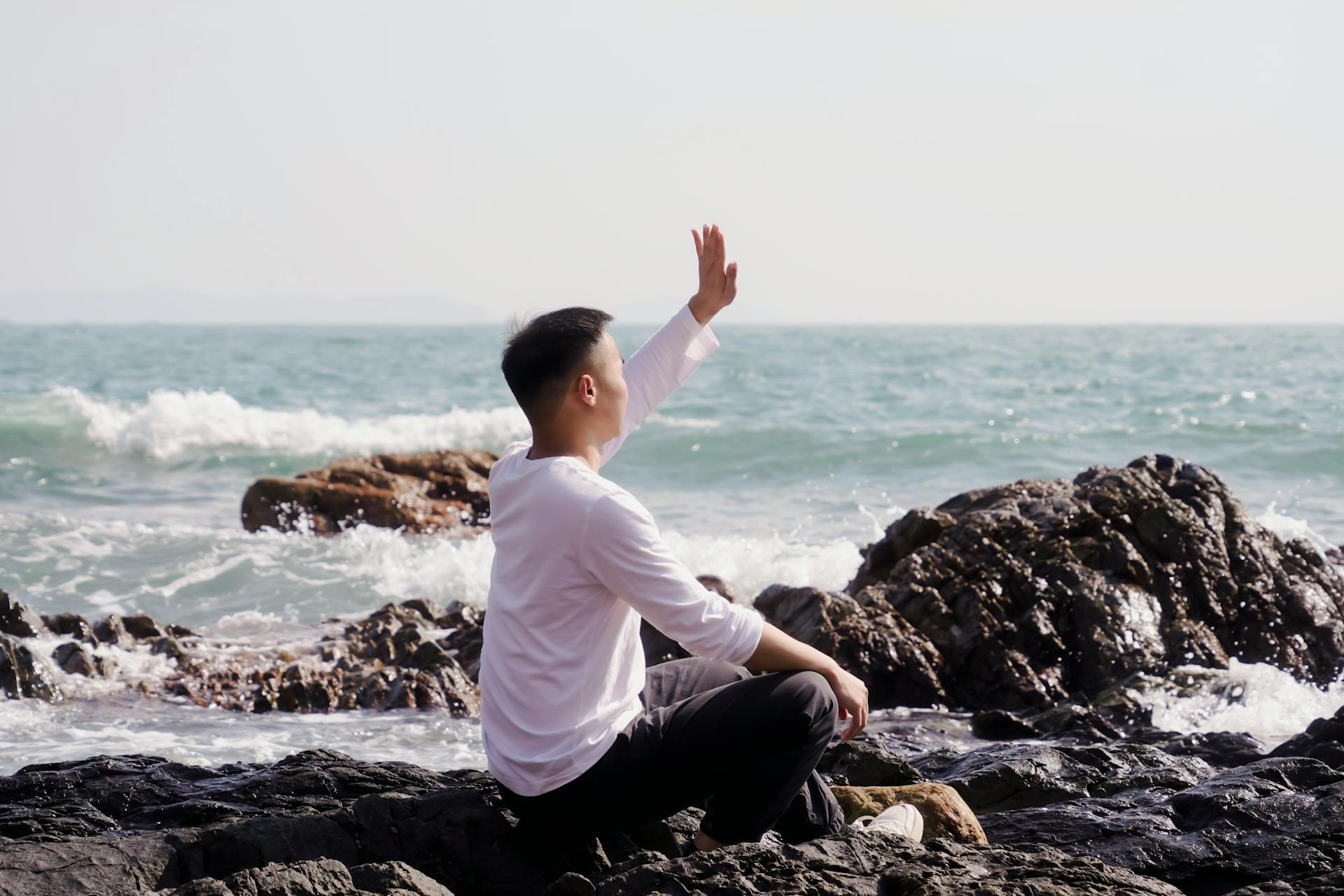 Un hombre sentado en una playa rocosa | Fuente: Pexels