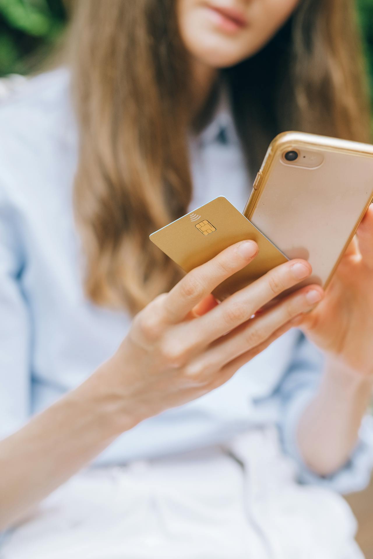 Una joven con su teléfono y su tarjeta de crédito | Fuente: Pexels