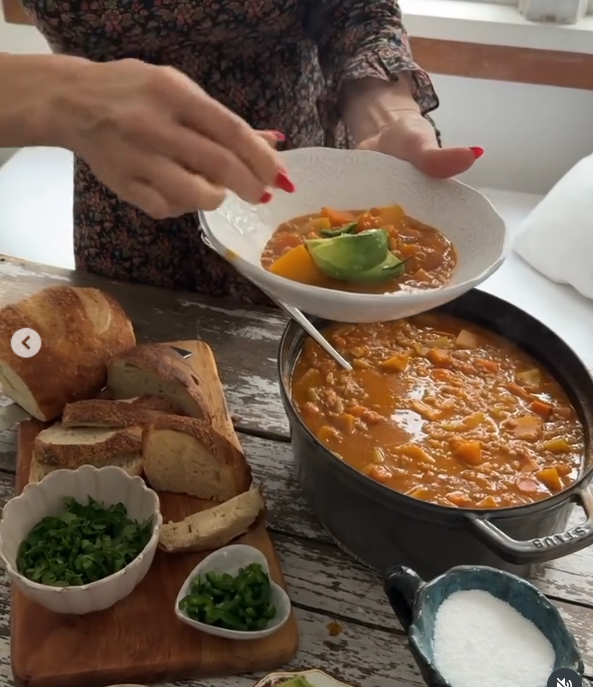 Pamela Anderson prepara un guiso de verduras casero en su acogedora cocina de la isla de Vancouver, y adorna un cuenco blanco con rodajas de aguacate fresco directamente desde una rústica mesa de madera. Rodeado de rebanadas de pan de masa madre crujiente, cilantro picado, pimientos cortados en dados y sal marina en escamas, este plato a base de plantas refleja su pasión por las comidas nutritivas, directamente del huerto a la mesa. Acompañó el vídeo de cocina con este inspirador comentario: "Descubre la belleza que hay en ti y luego compártela. 🤍". | Fuente: Instagram/pamelaanderson