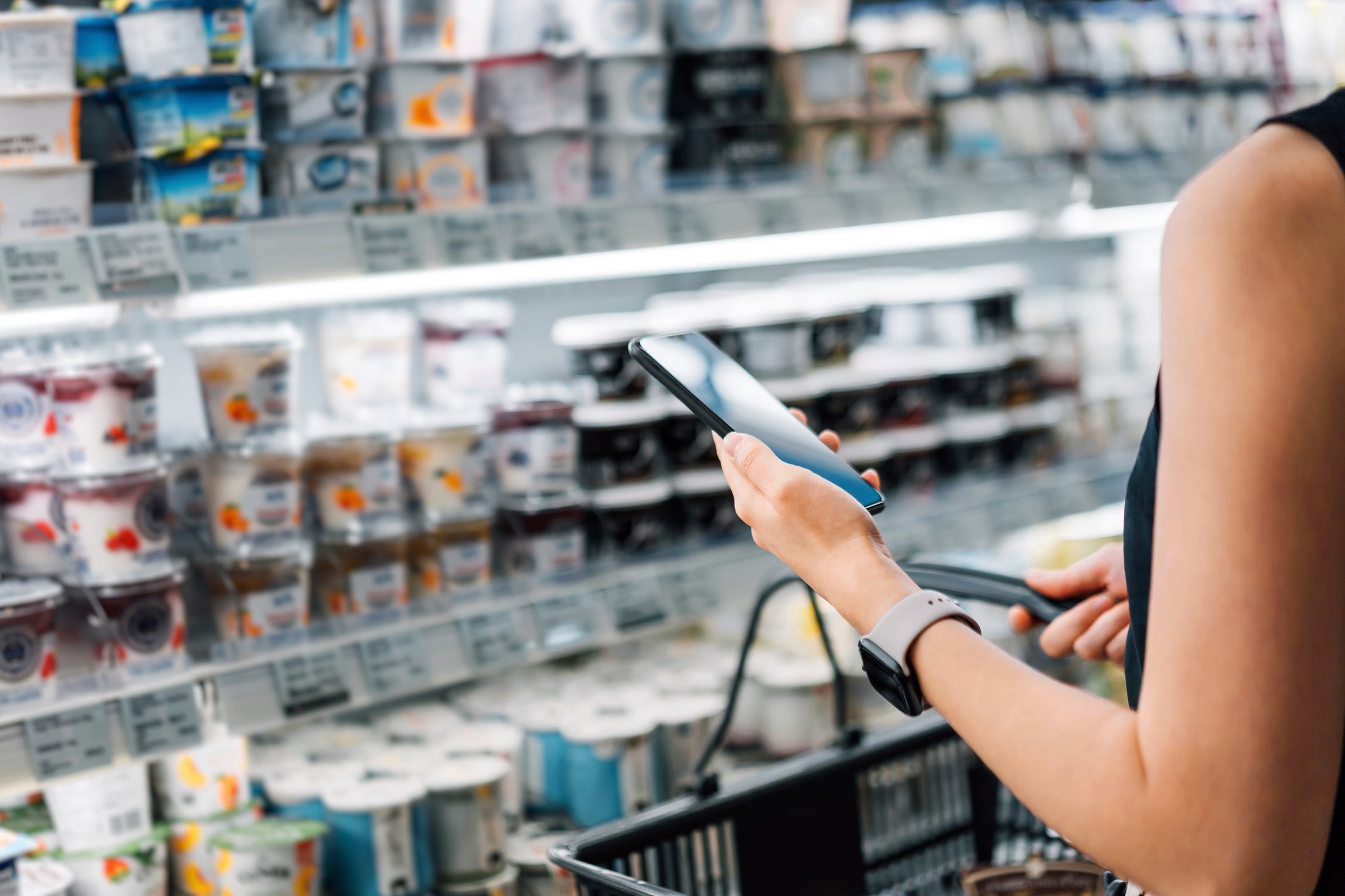 Una mujer en un supermercado con un carro de compras sostiene un celular. | Foto: Getty Images