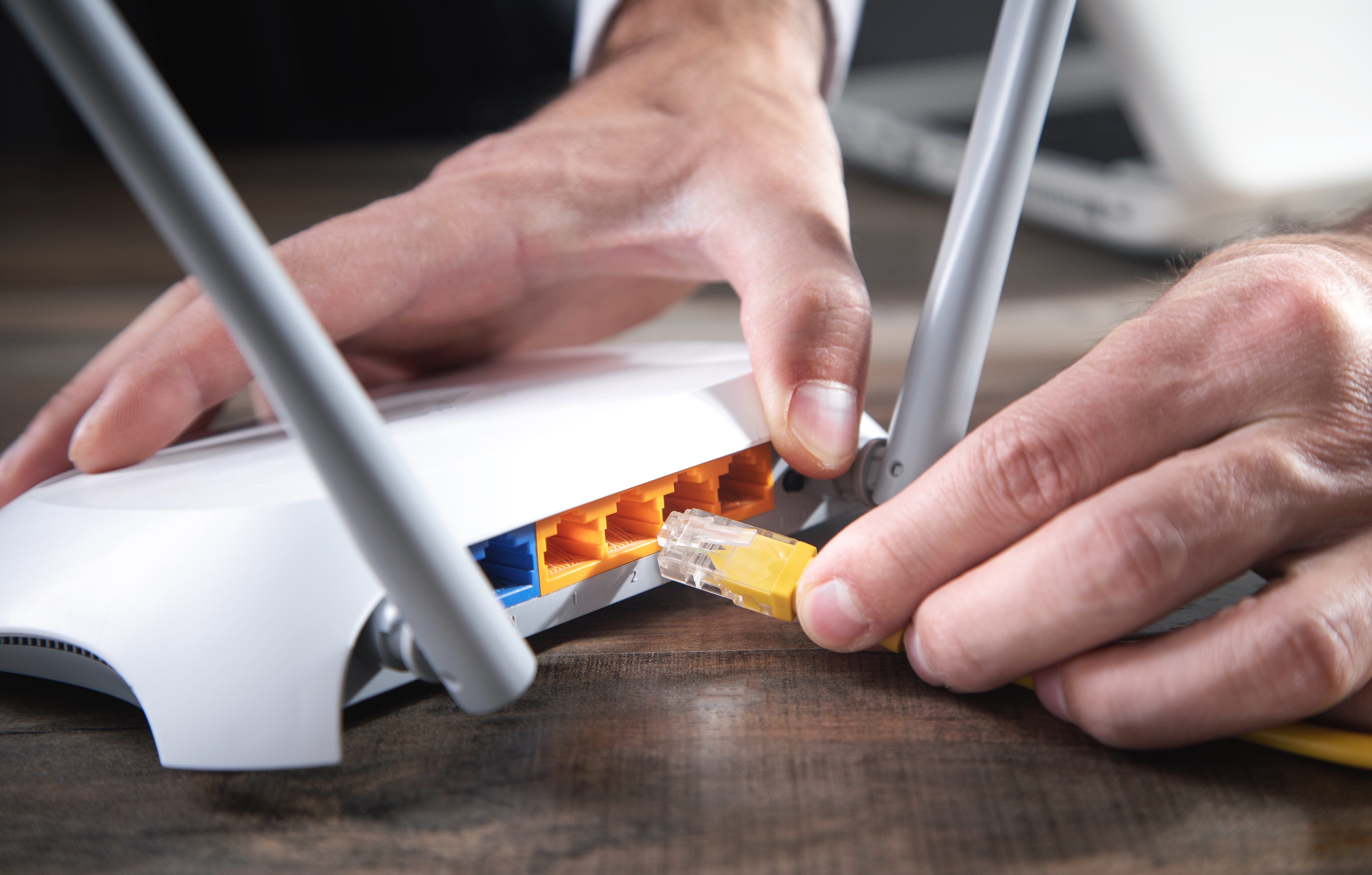 Un hombre enchufando un cable a un router de internet | Fuente: Shutterstock