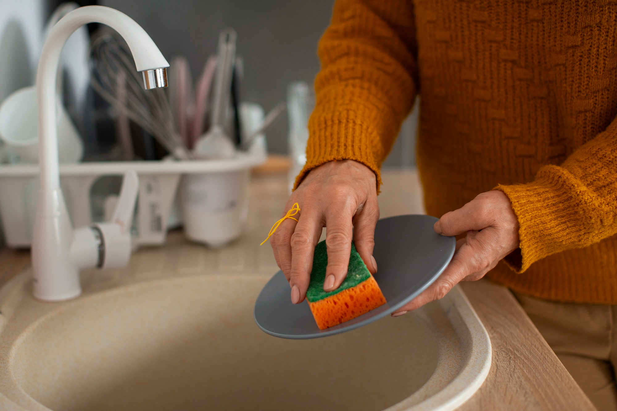 Una mujer limpiando un plato con una esponja | Fuente: Freepik