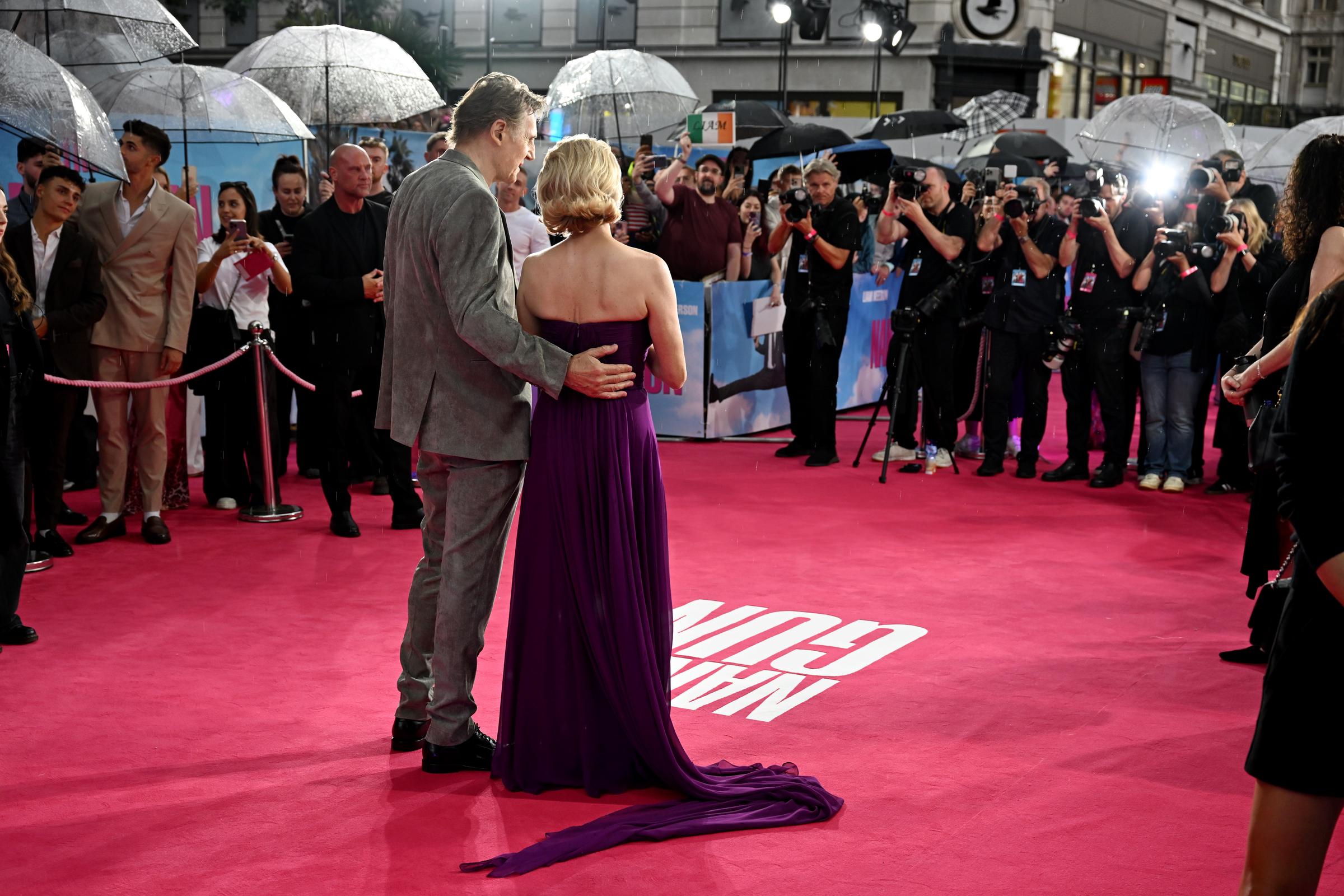 Liam Neeson sostiene a Pamela Anderson por la cintura mientras la pareja posa para las fotos en el estreno en el Reino Unido de "The Naked Gun" en Cineworld Leicester Square, en Londres, Inglaterra, el 22 de julio de 2025 | Fuente: Getty Images