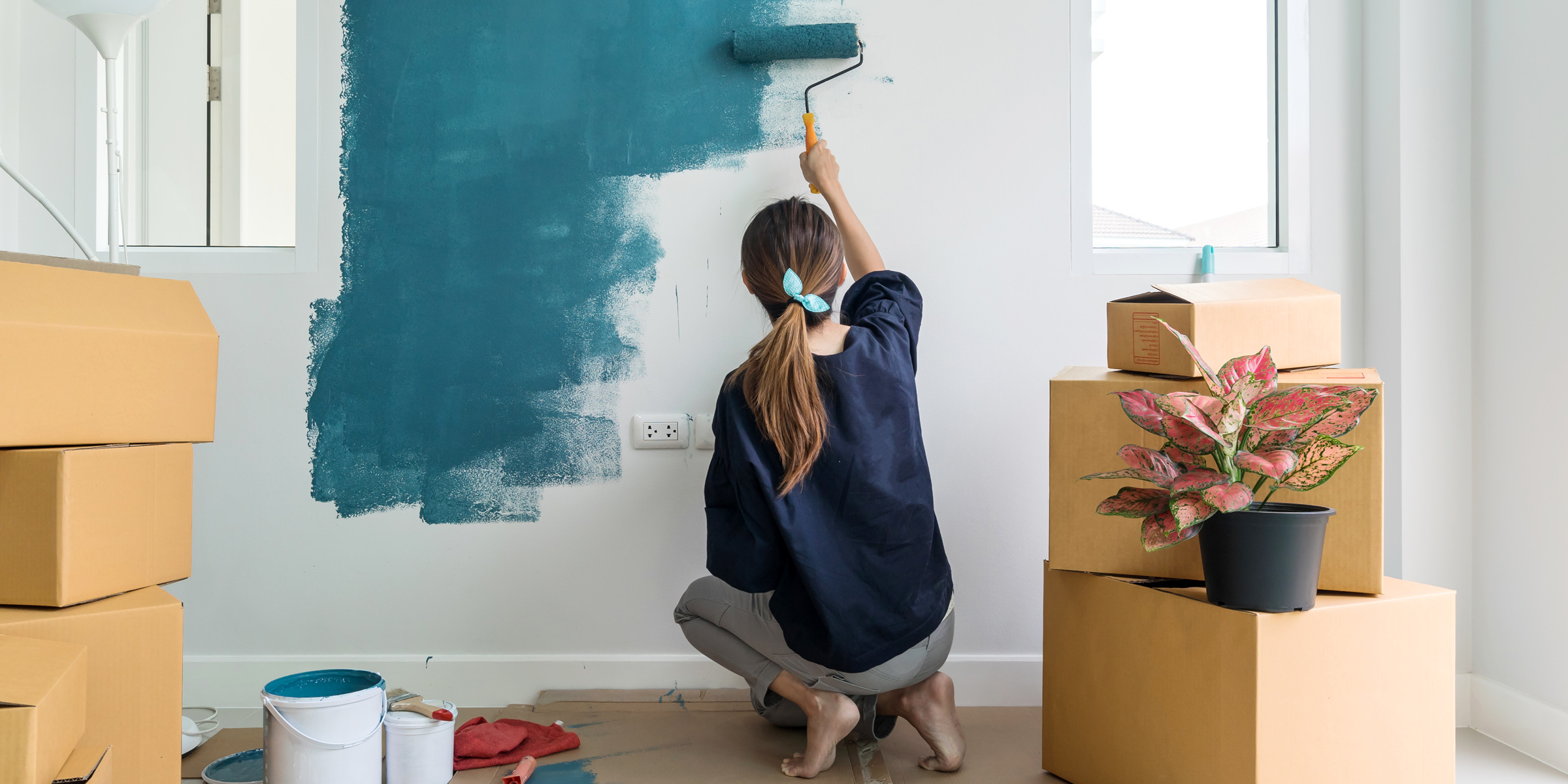 Una mujer pintando una pared | Fuente: Shutterstock