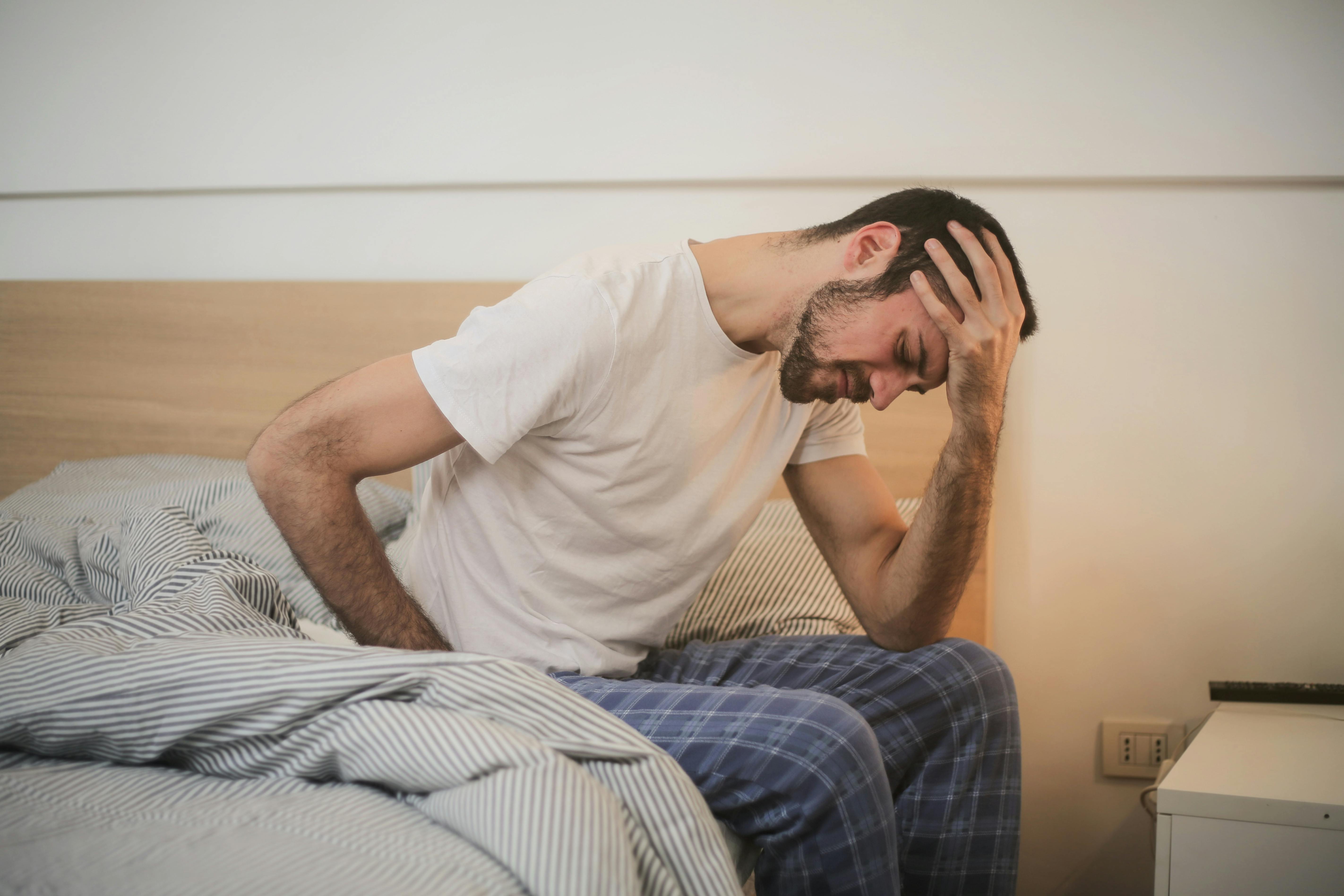 Un hombre estresado sentado en una cama | Fuente: Pexels