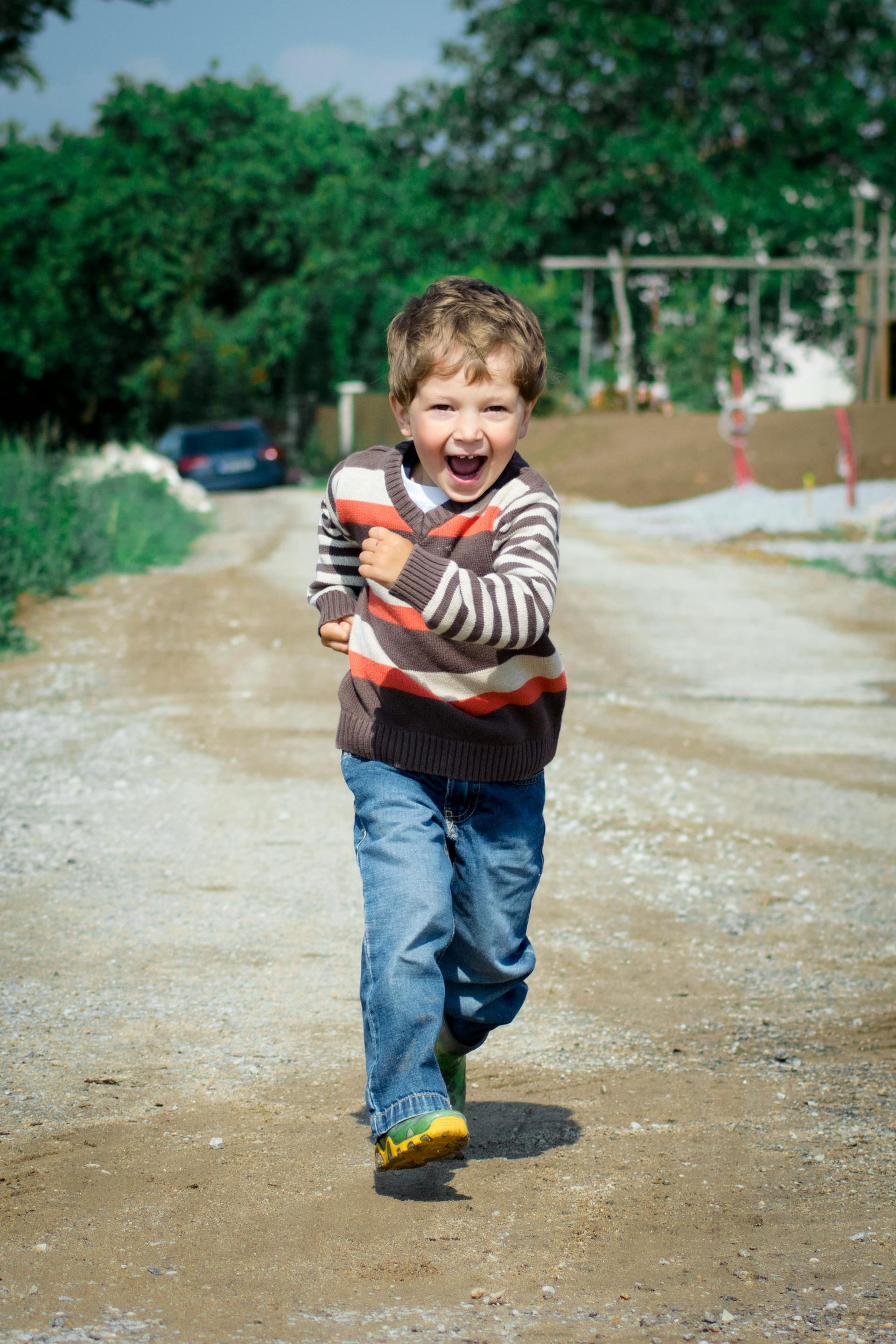 Un niño feliz corriendo por la carretera | Fuente: Pexels