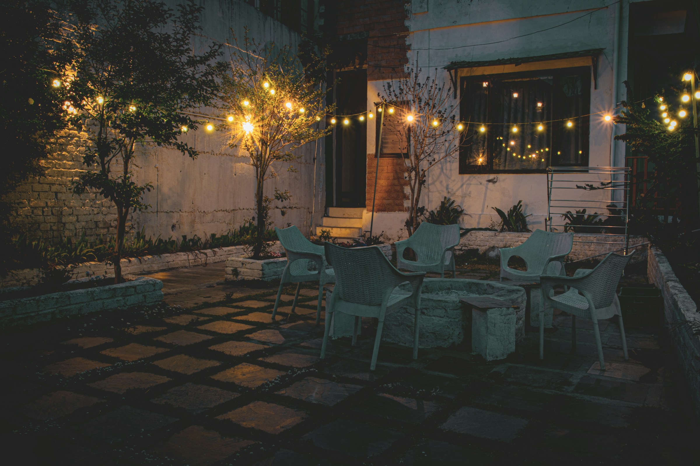 Vista lejana de un patio con luces amarillas, mesas y sillas | Fuente: Unsplash
