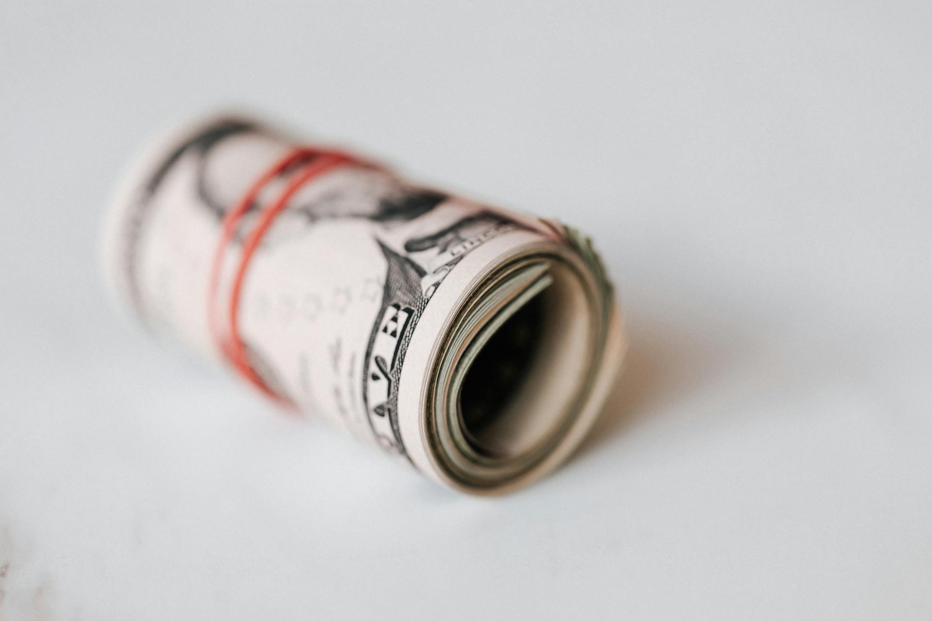 Una goma elástica roja enrollada alrededor de billetes de un dólar | Fuente: Pexels